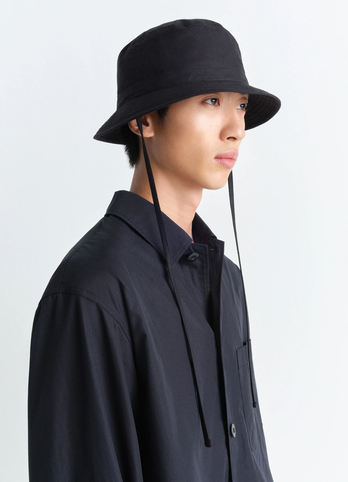 Lemaire Desert Bucket Hat in Black Ventile Cotton, model shot, Side view Tied straps