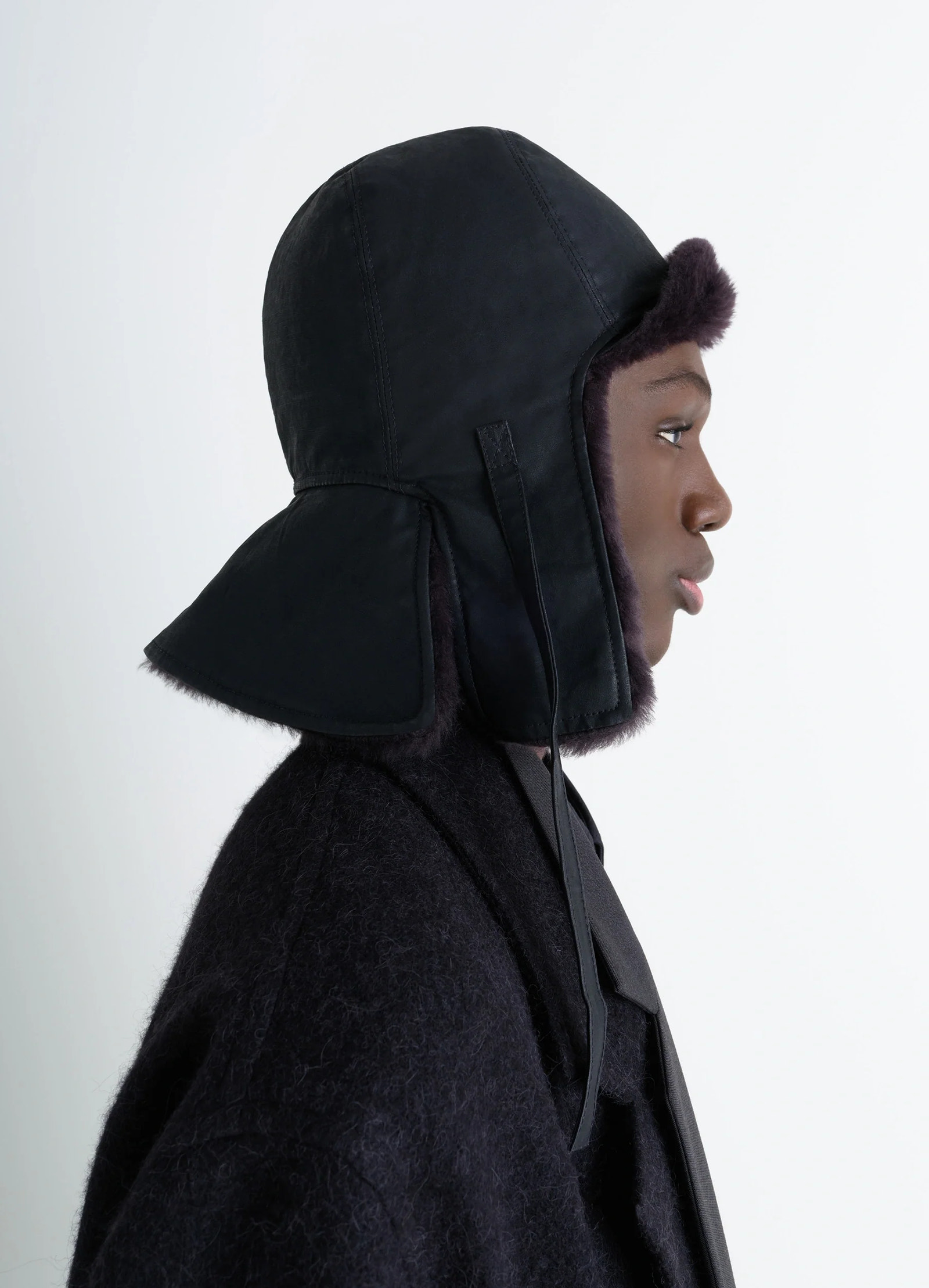 Lemaire reversible shearling chapka in black water-repellent cotton, model shot, side view inspired by aviator hats
