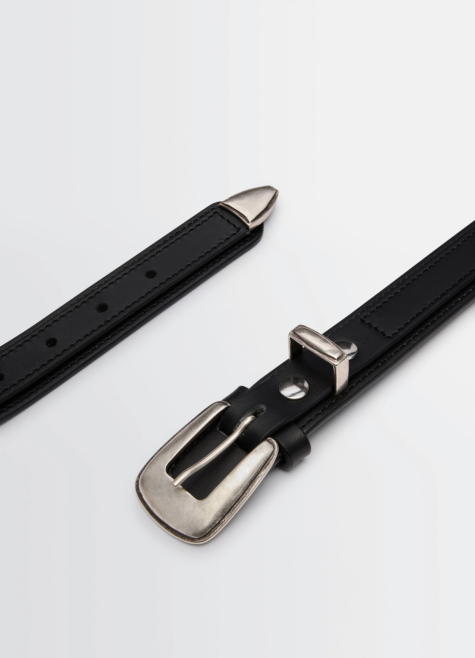Lemaire minimal western belt in black smooth leather, product shot, angled close-up silver tip accent