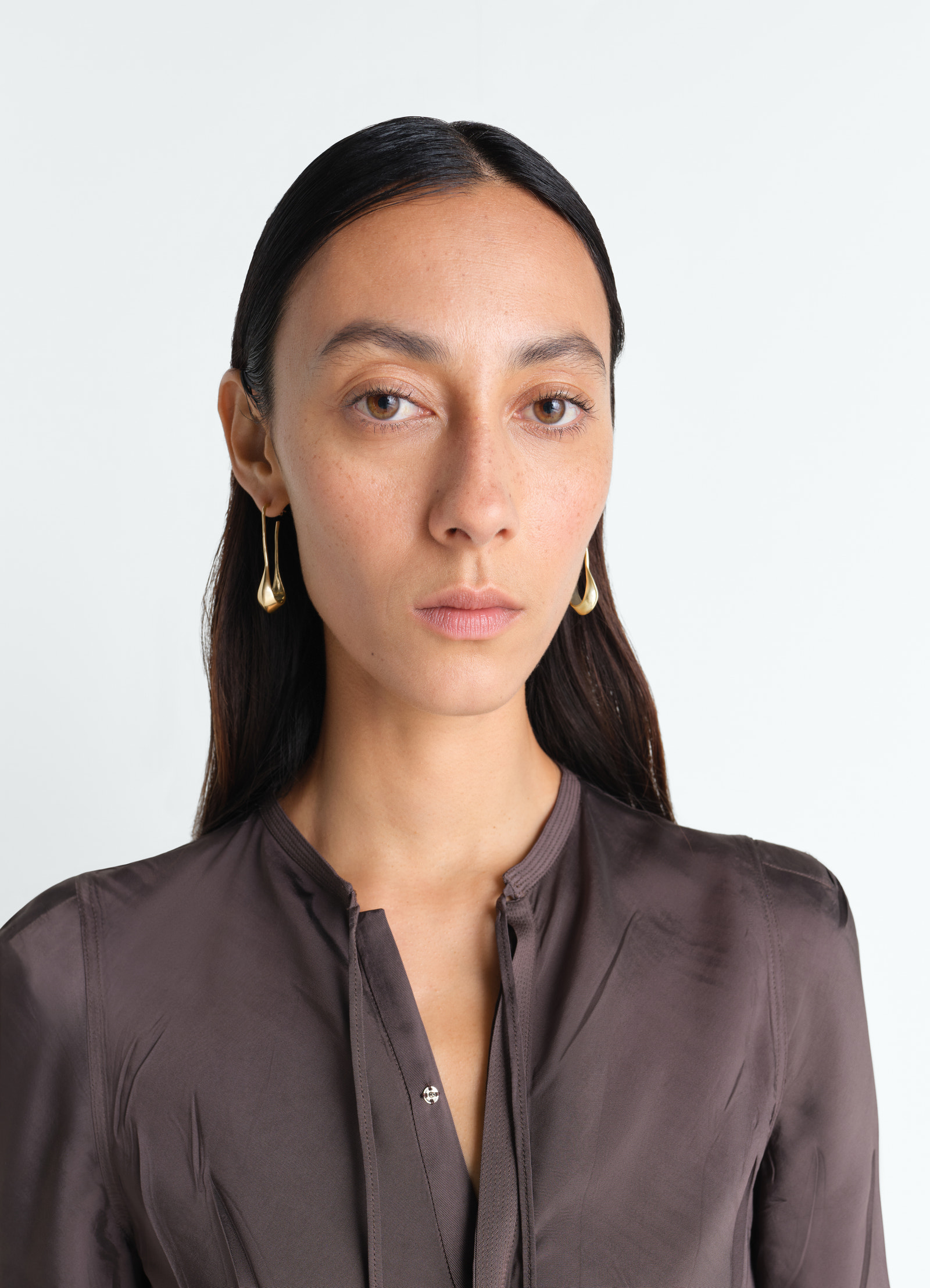 Short gold vermeil drop earrings by lemaire worn by a model in a close-up front shot