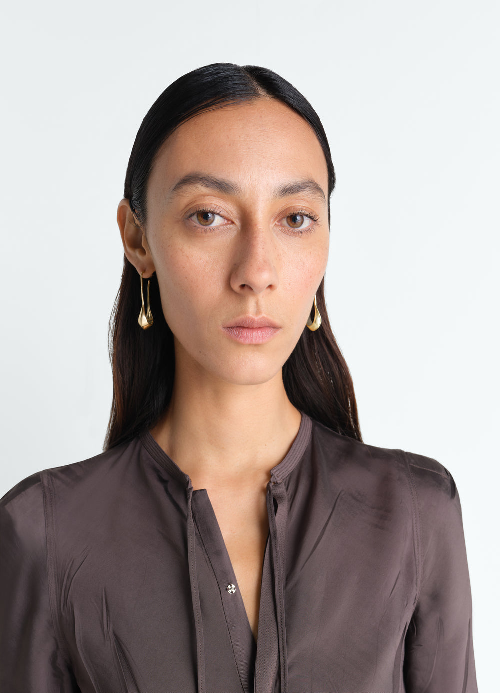 Short gold vermeil drop earrings by LEMAIRE worn by a model in a close-up front shot