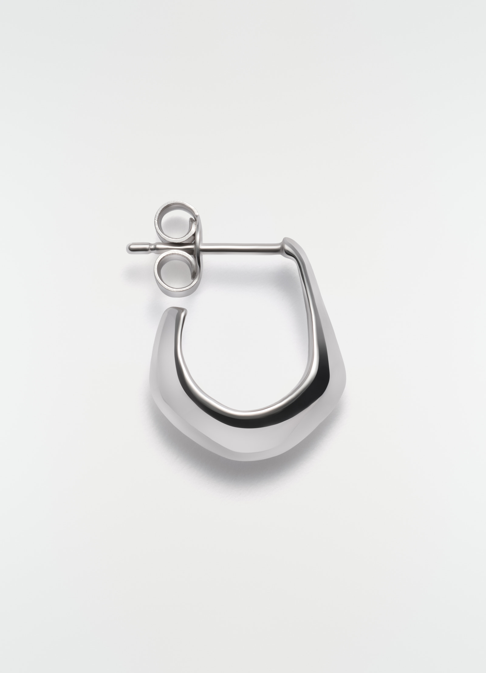 Mini silver metal drop earring by lemaire on plain white background close-up detail