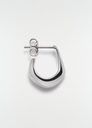 Mini silver metal drop earring by lemaire on plain white background close-up detail