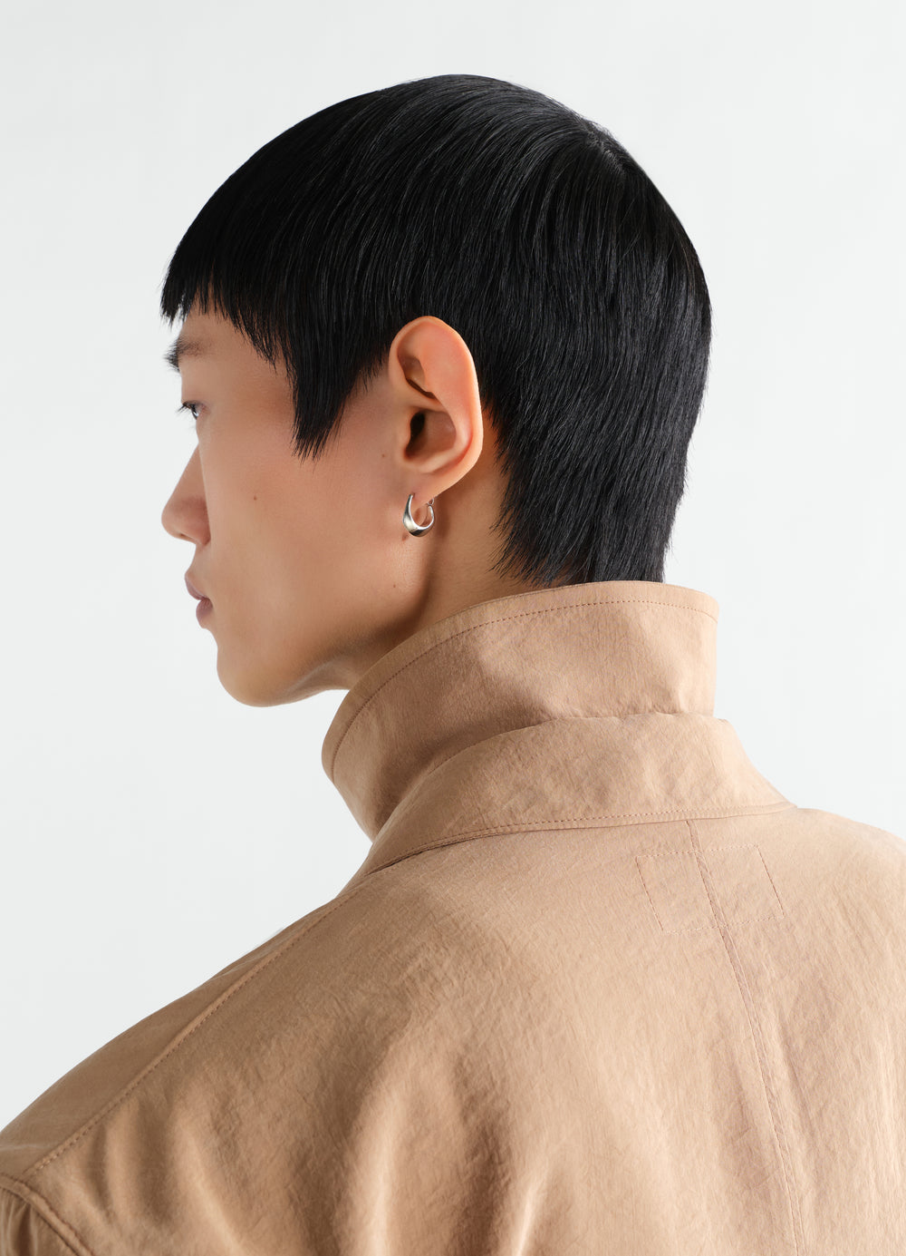 Mini Drop Earring in silver worn by a model with black hair and beige collar jacket LEMAIRE side view