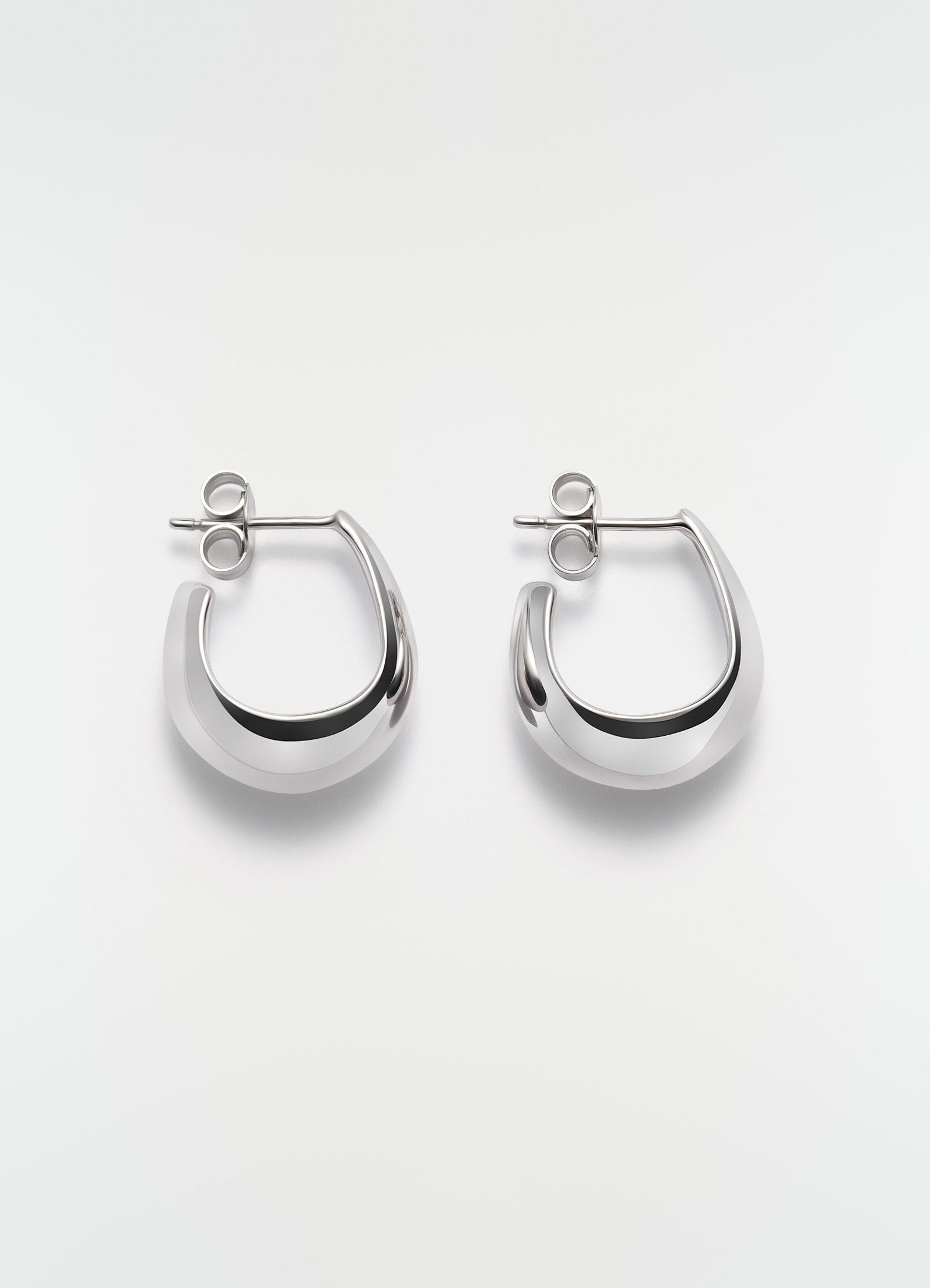 Curved mini drop silver earrings in polished metal by lemaire on plain white background front view