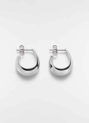 Curved mini drop silver earrings in polished metal by lemaire on plain white background front view