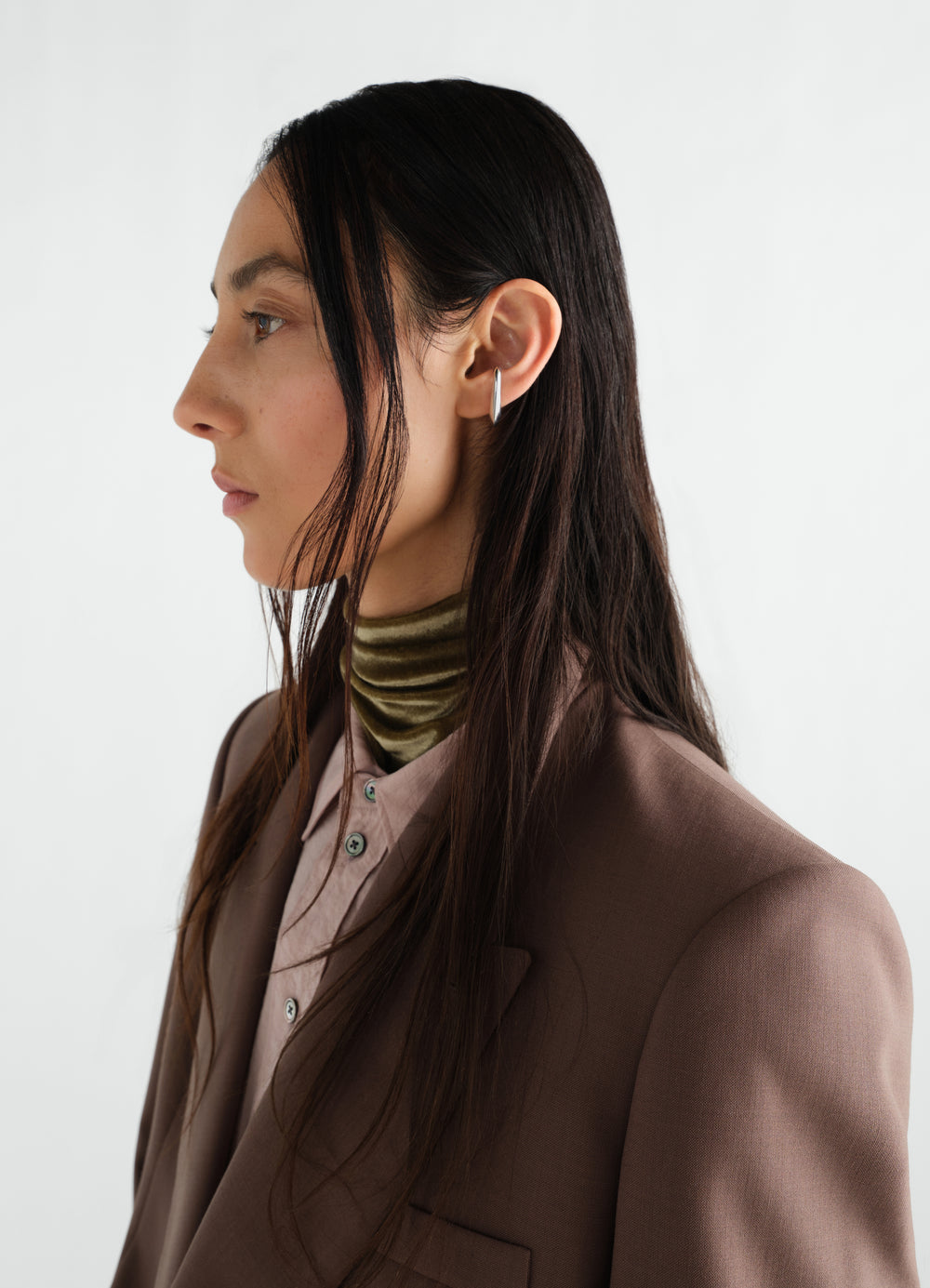 Long drop silver earcuff LEMAIRE worn by a model side profile with brown blazer and olive velvet turtleneck
