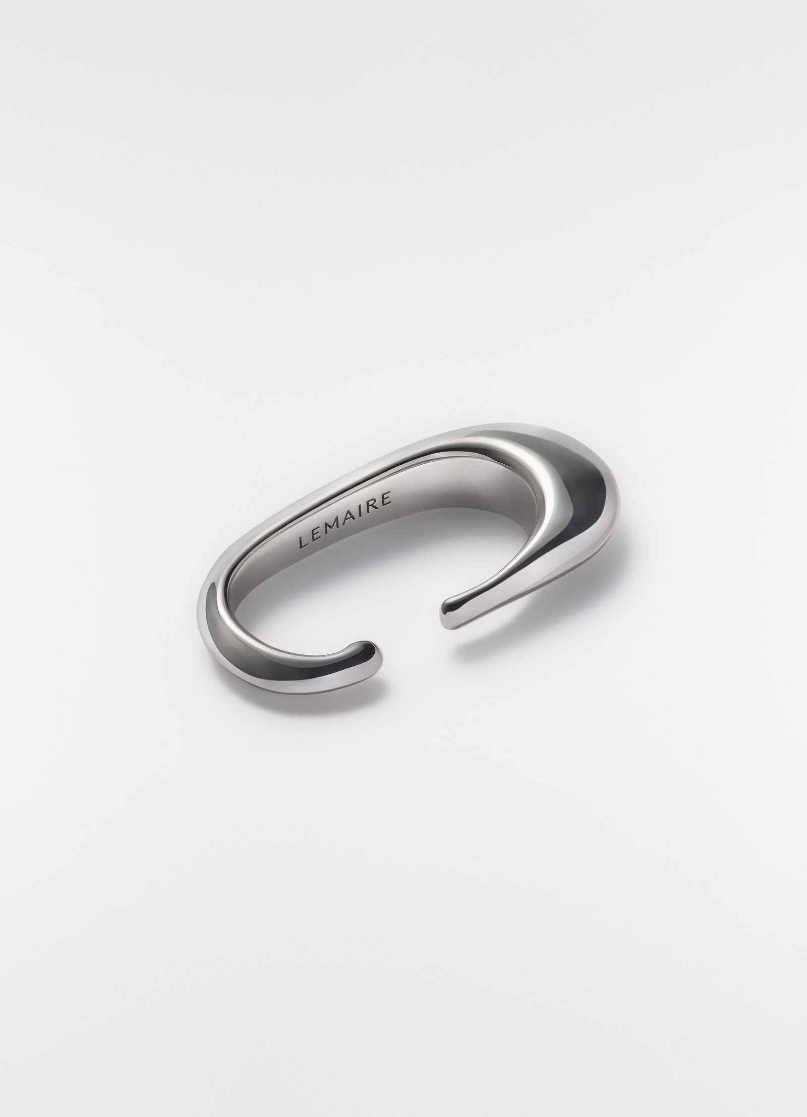 Long drop earcuff in silver metal lemaire styled on plain white background close-up detail