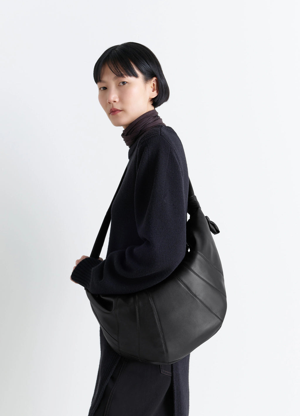 Lemaire Large Croissant Bag in Black Nappa Lamb Leather, model shot, three-quarter view soft drape curve