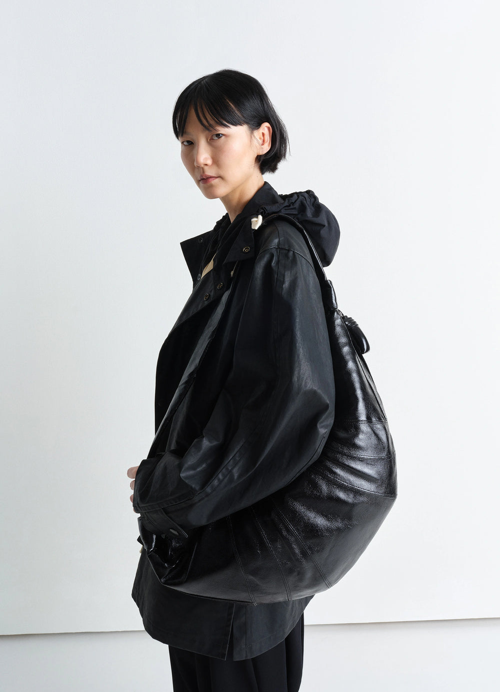 Lemaire Large Croissant Bag in Black Coated Cotton Canvas, model shot, Side view Shiny textured finish