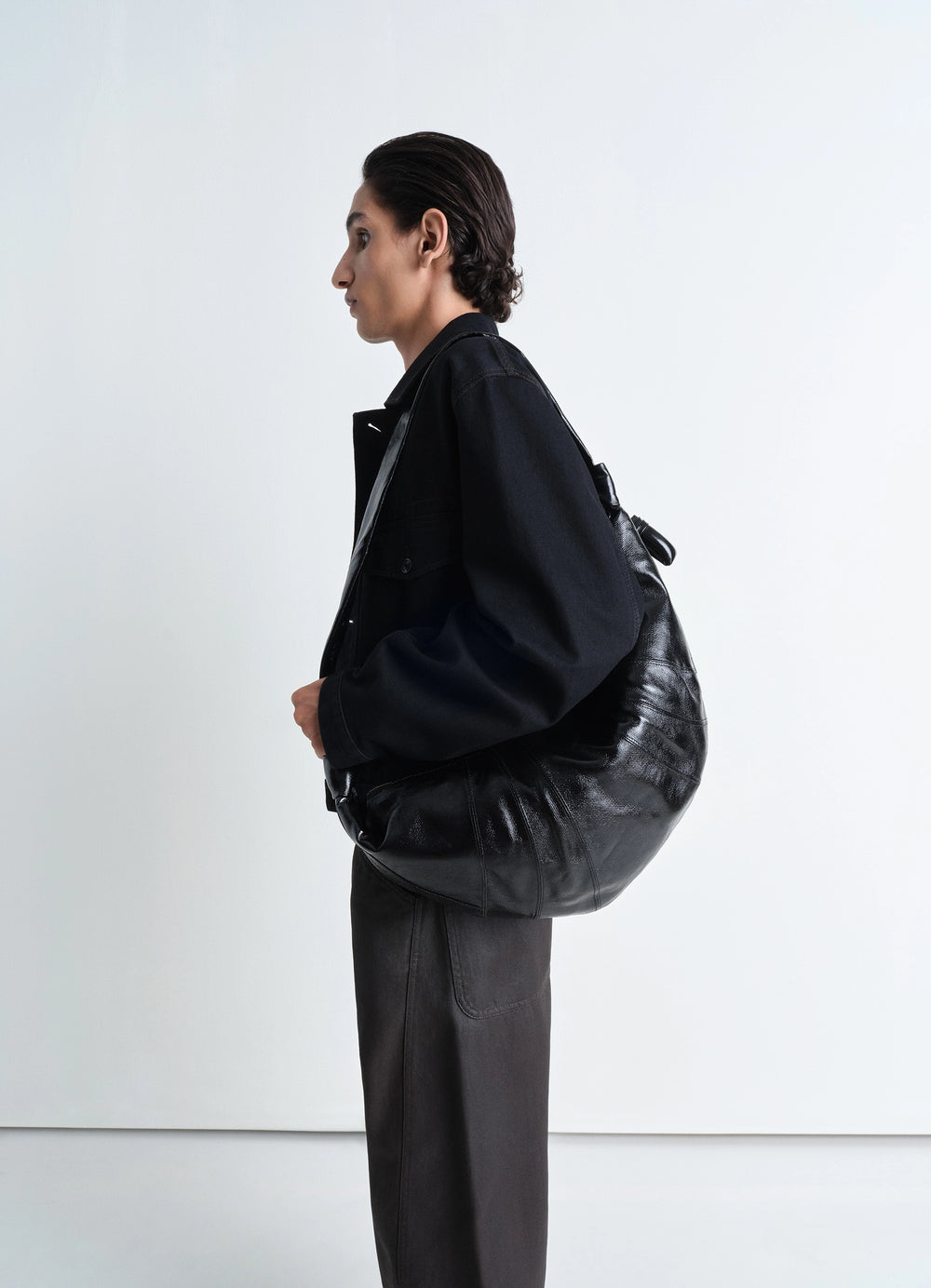 Lemaire Large Croissant Bag in Black Coated Cotton Canvas, model shot, three-quarter view slouchy ergonomic fit