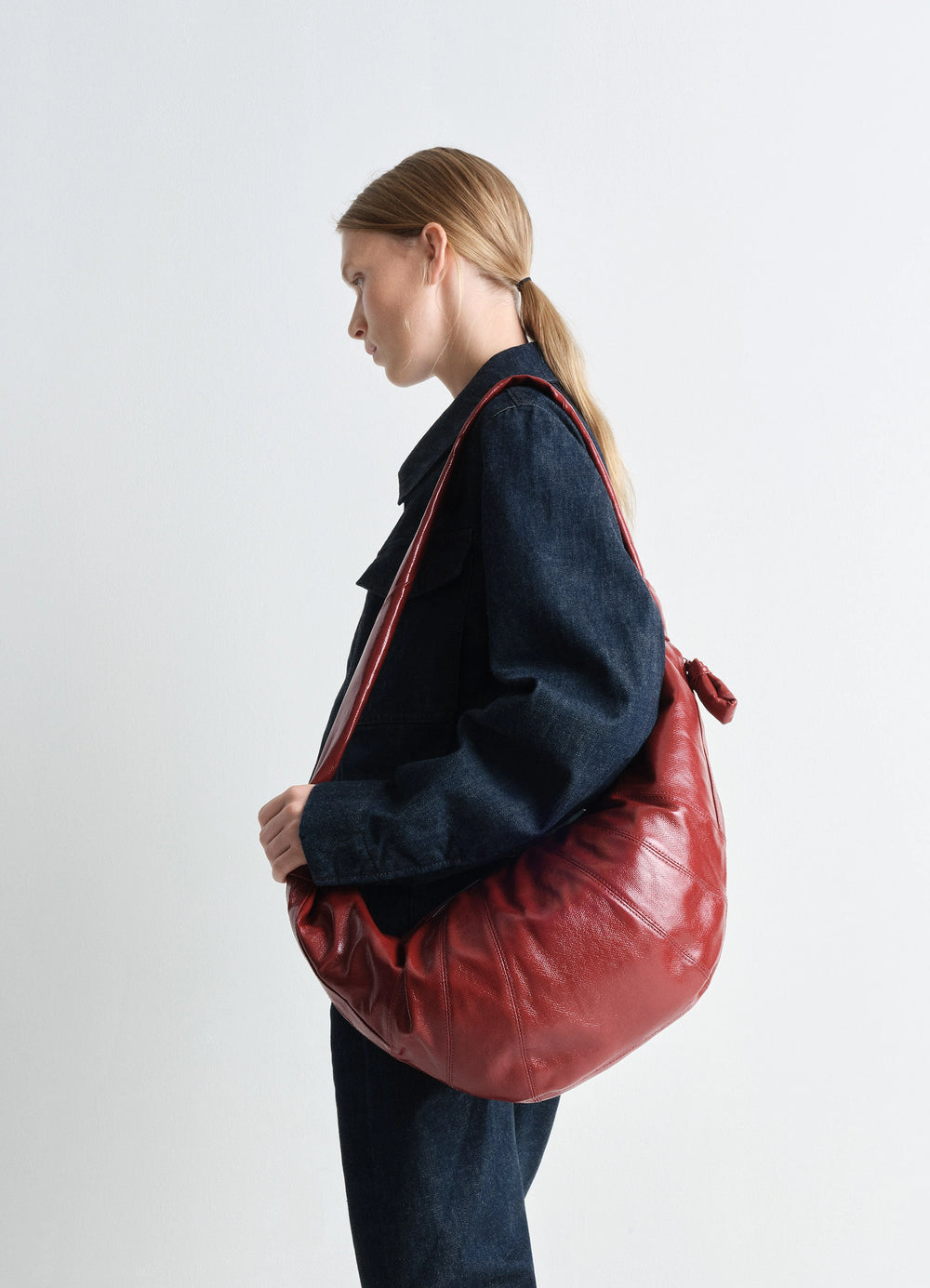 Lemaire Large Croissant Bag in Red coated cotton canvas, model shot, over-shoulder view slouchy silhouette