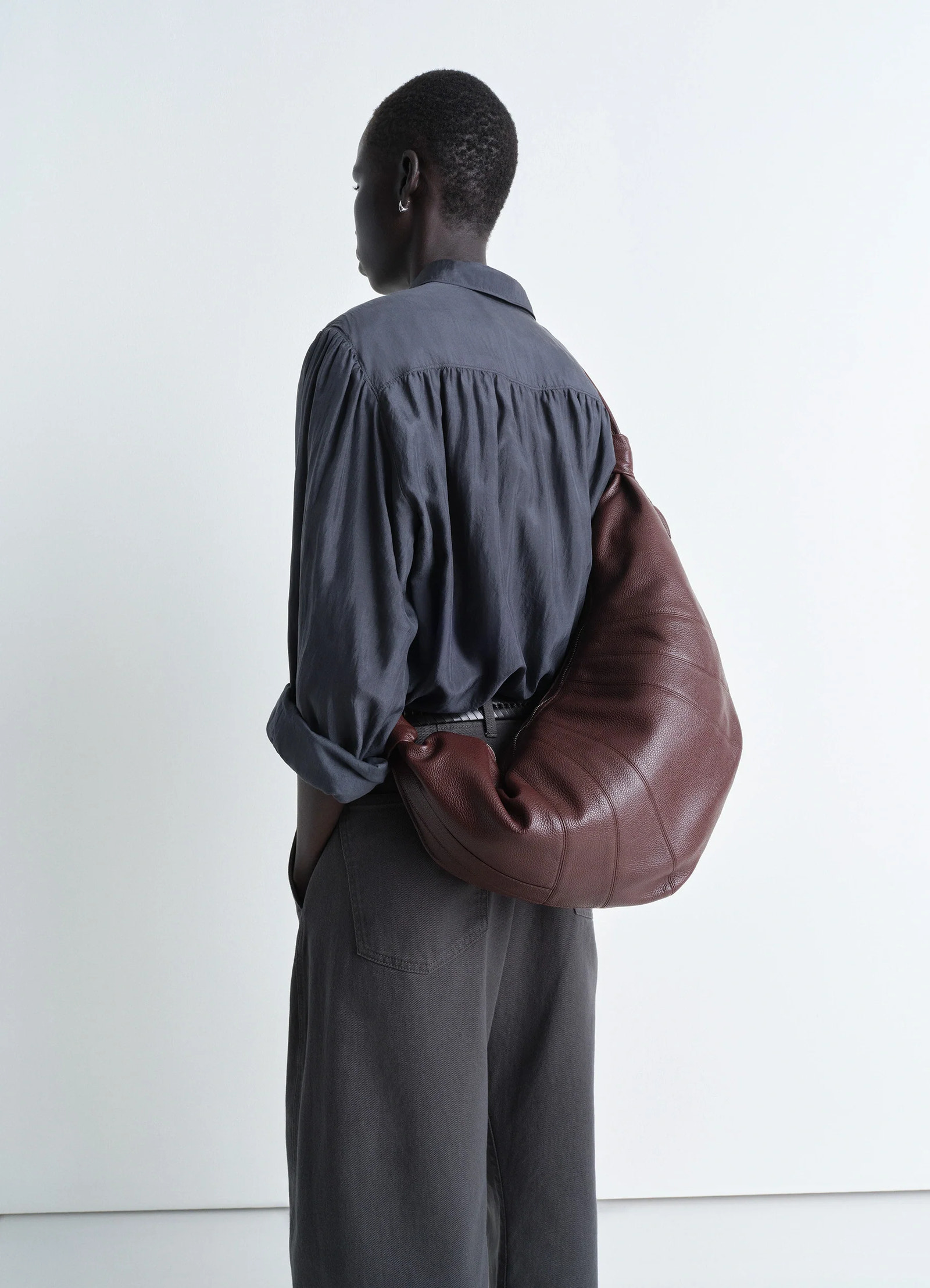Lemaire large croissant bag in grained leather, model shot, back angle draped over shoulder