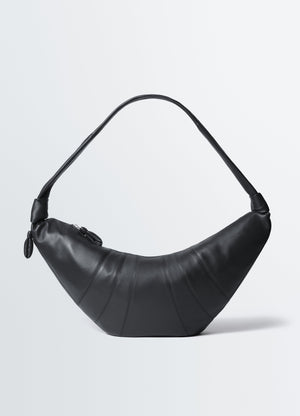 Large black leather croissant bag with shoulder strap and zipper by lemaire on white background front view