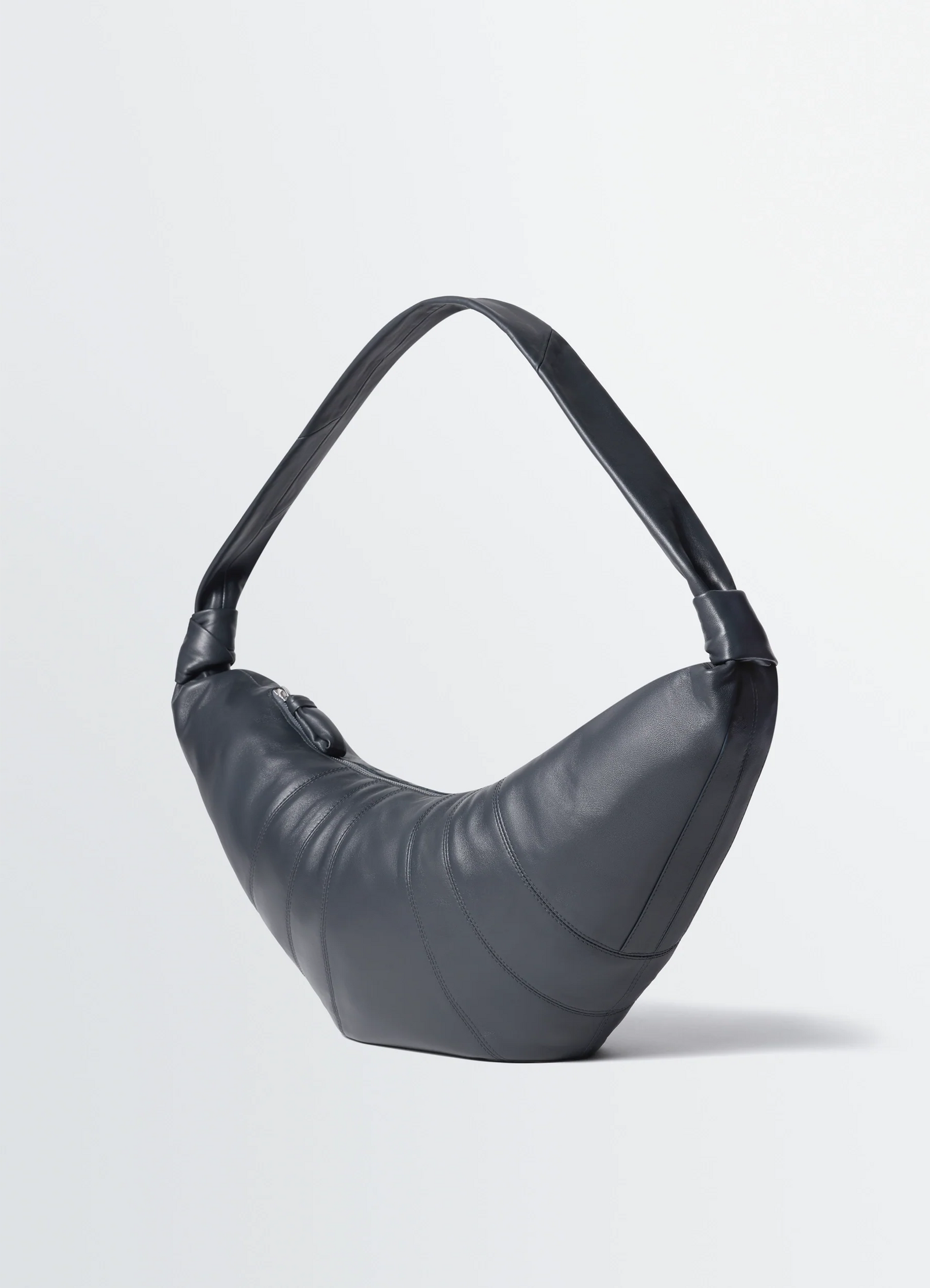Lemaire large croissant bag in nappa lamb leather, product shot, three-quarter rear view asymmetrical top handle