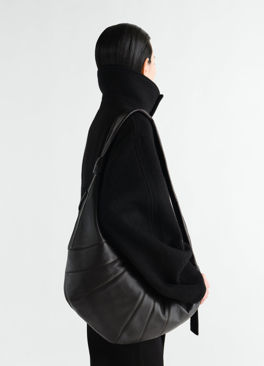 Sac Croissant grand modèle, coloris noir, porté par un mannequin, vue de profil, col visible