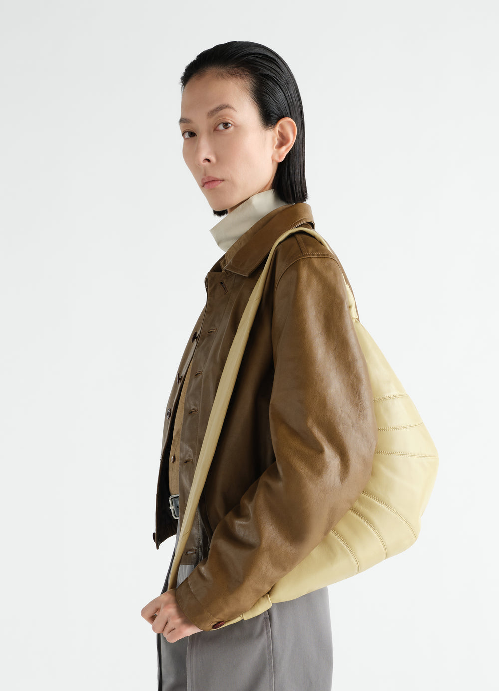 Medium yellow leather Croissant Bag LEMAIRE worn by a model side view with brown leather jacket