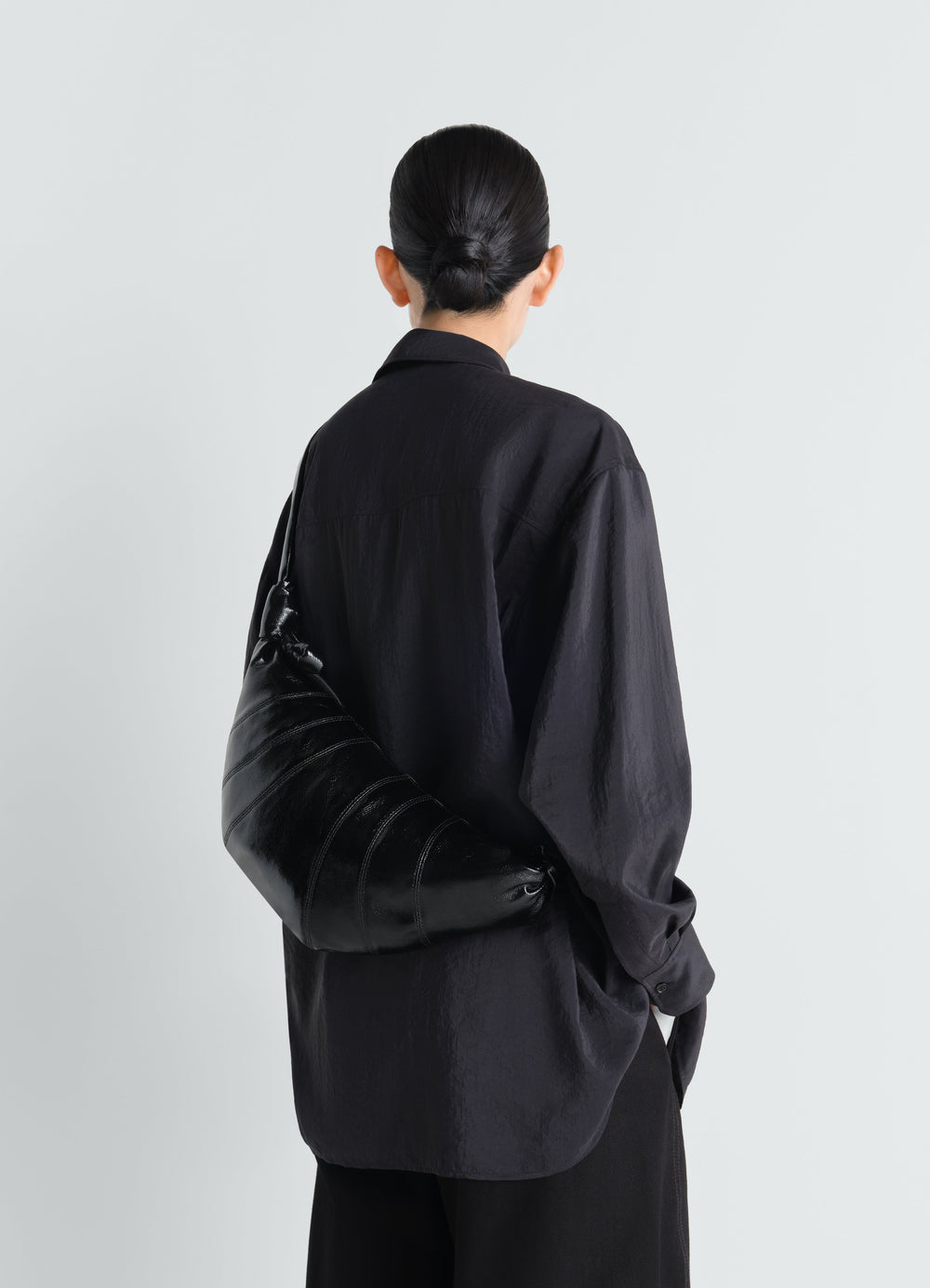 Medium Croissant Bag in black coated cotton worn by model with black shirt back view LEMAIRE