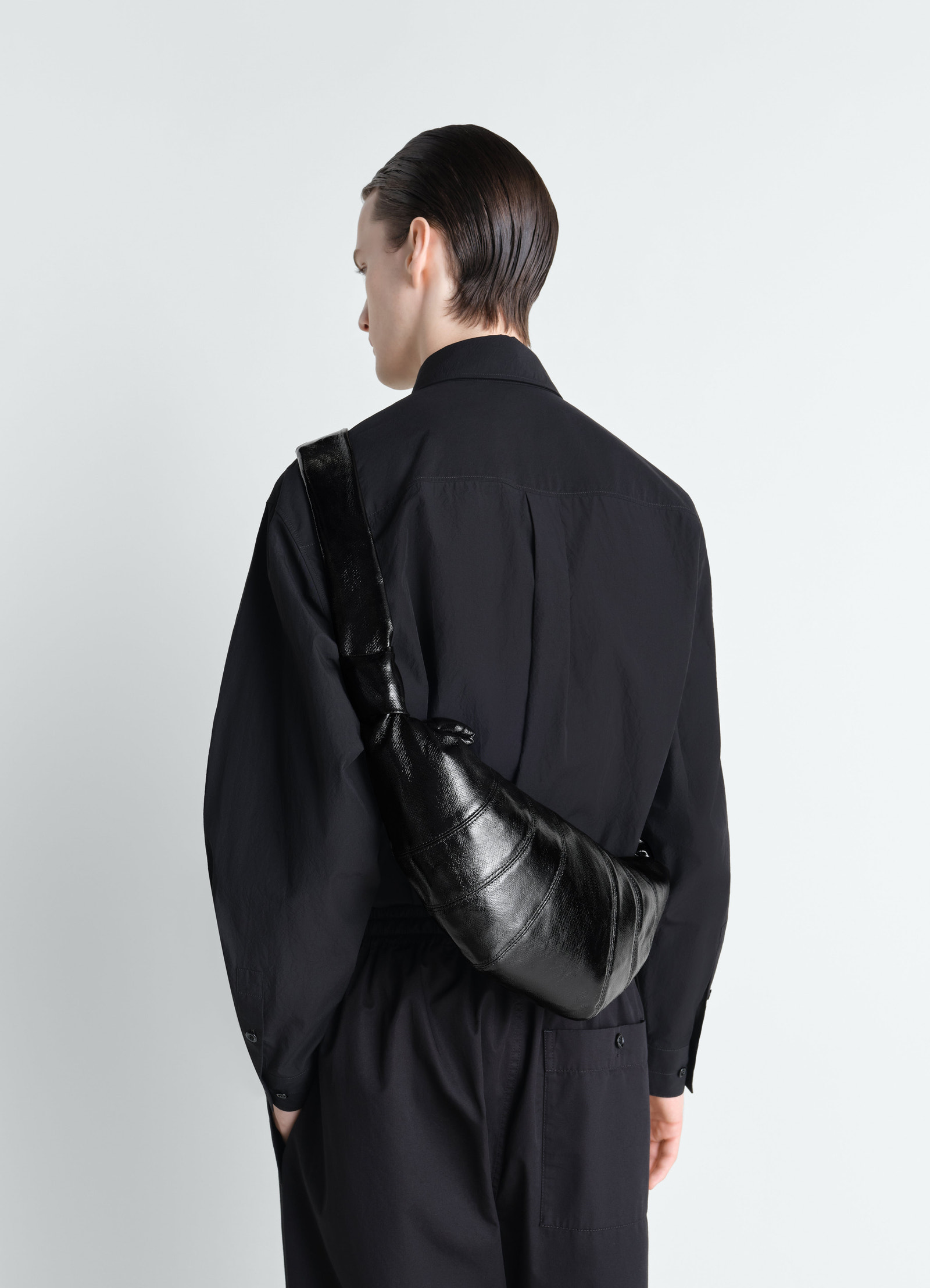 Medium croissant bag in black coated cotton lemaire worn by model back view against white background
