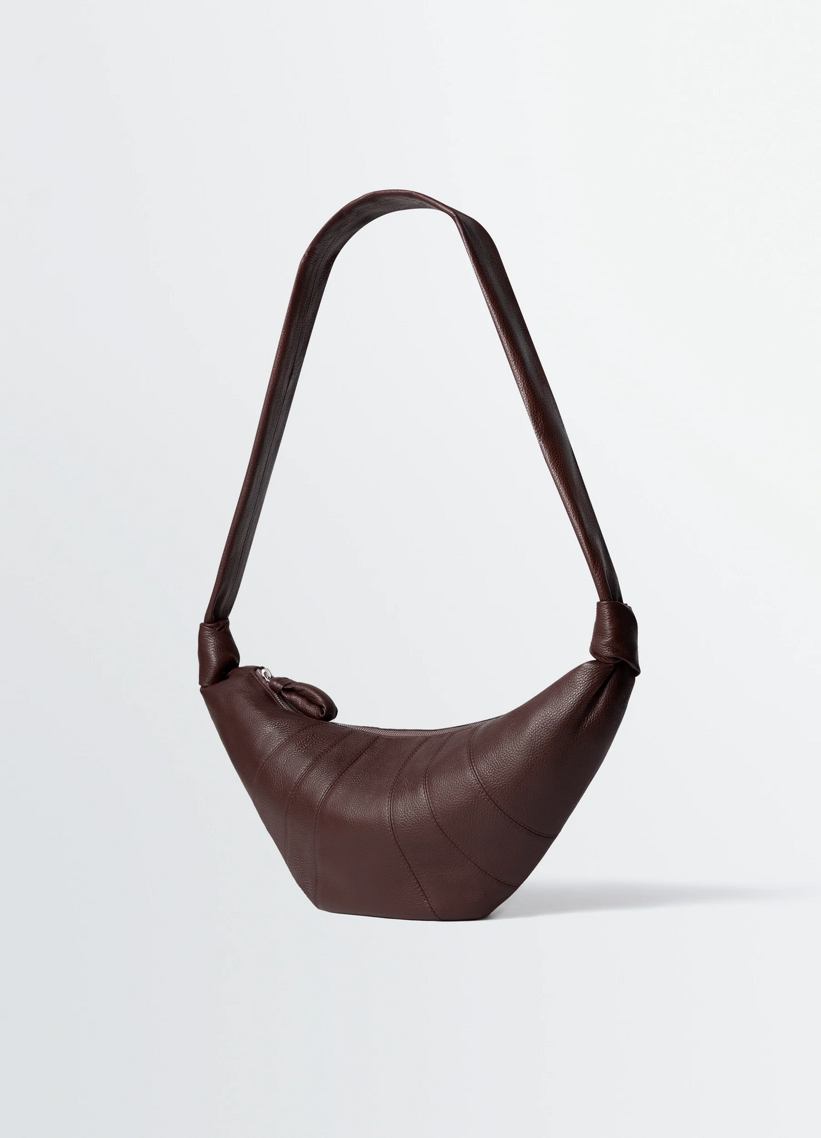 Medium croissant bag in grained leather, product shot, three-quarter view knotted strap detail