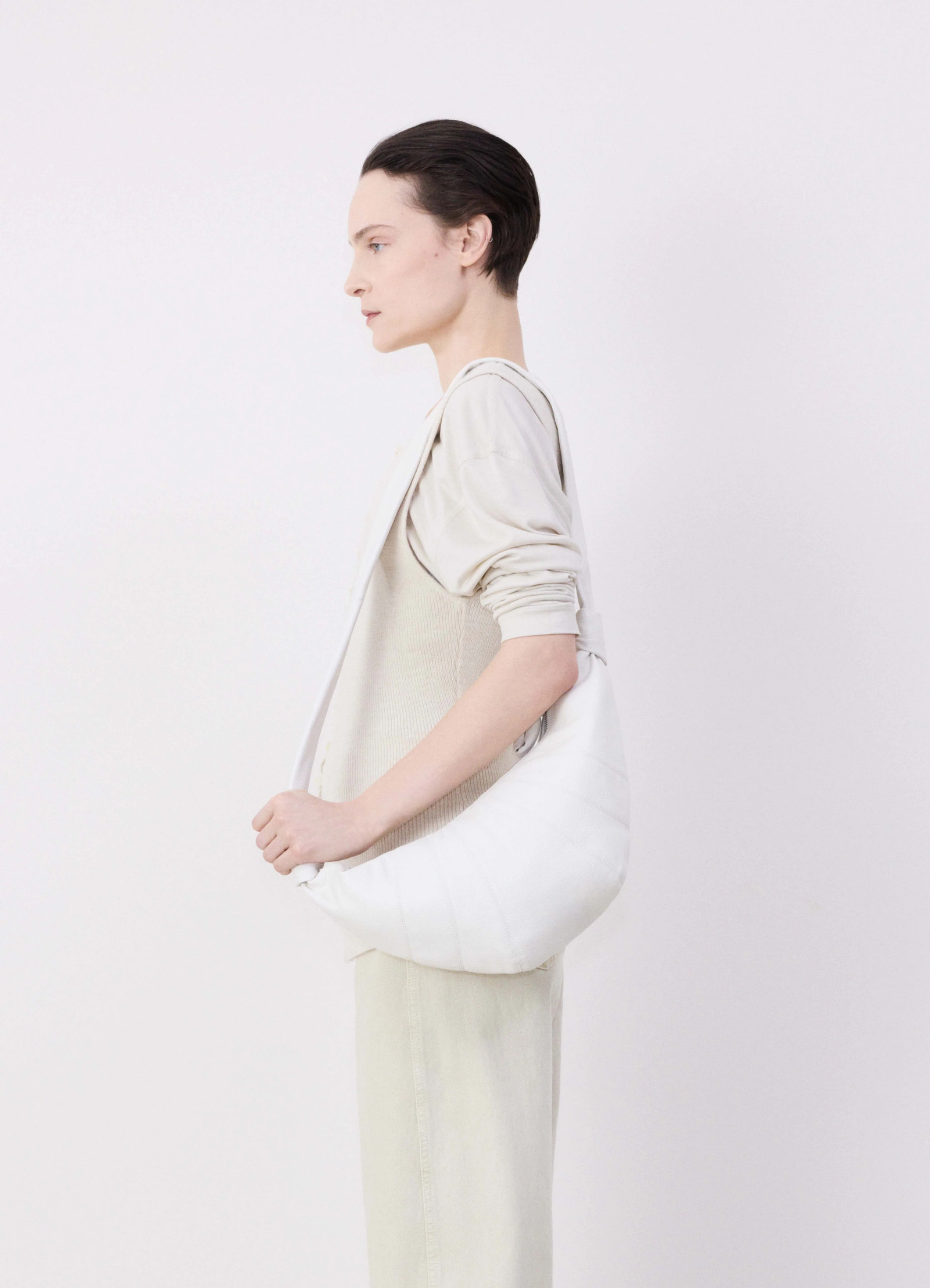 Lemaire medium croissant bag in soft grained leather white, model shot, profile view carried underarm holding