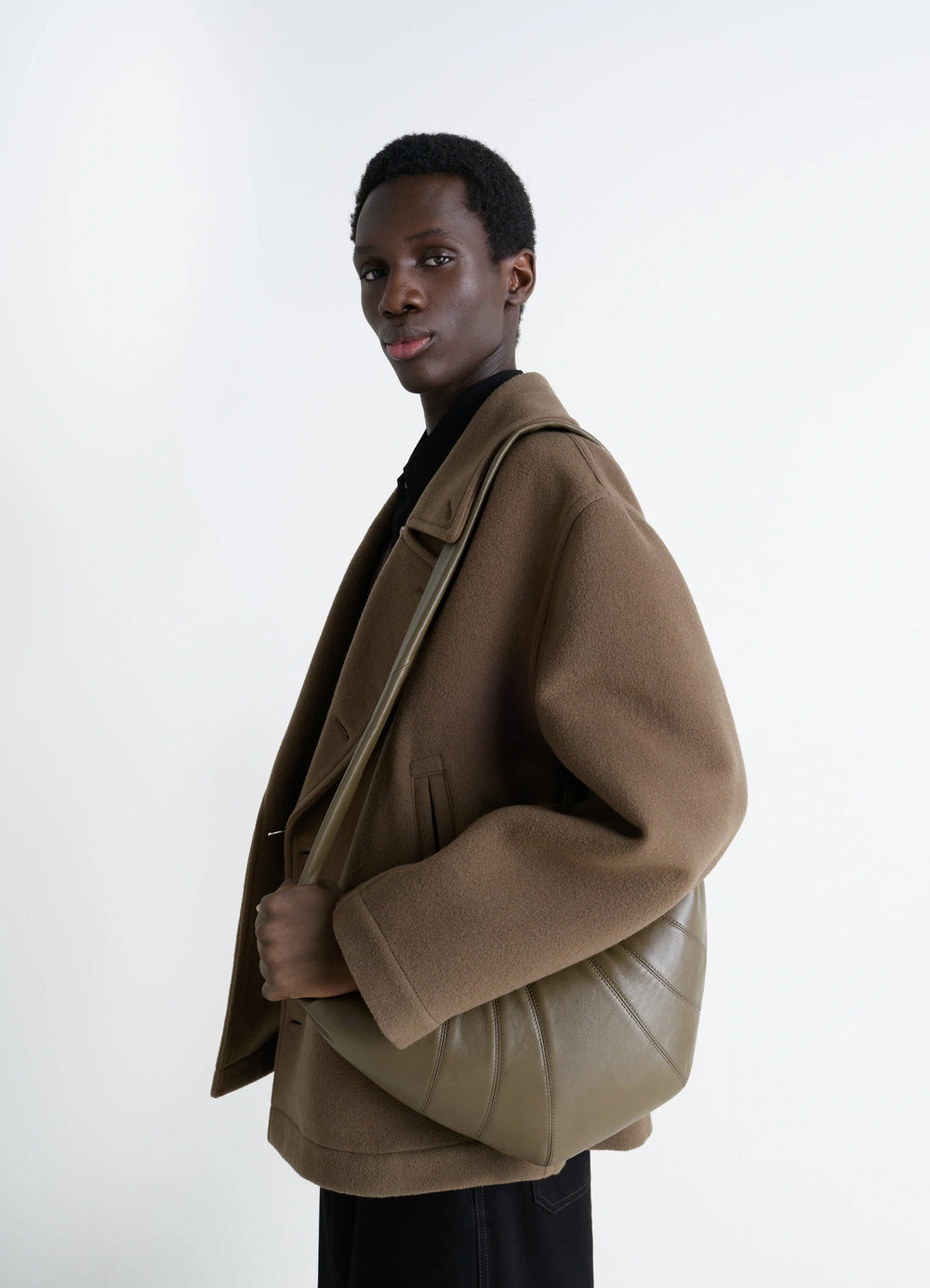 Lemaire Medium Croissant Bag in Nappa Lamb Leather, model shot, three-quarter view over shoulder with coat