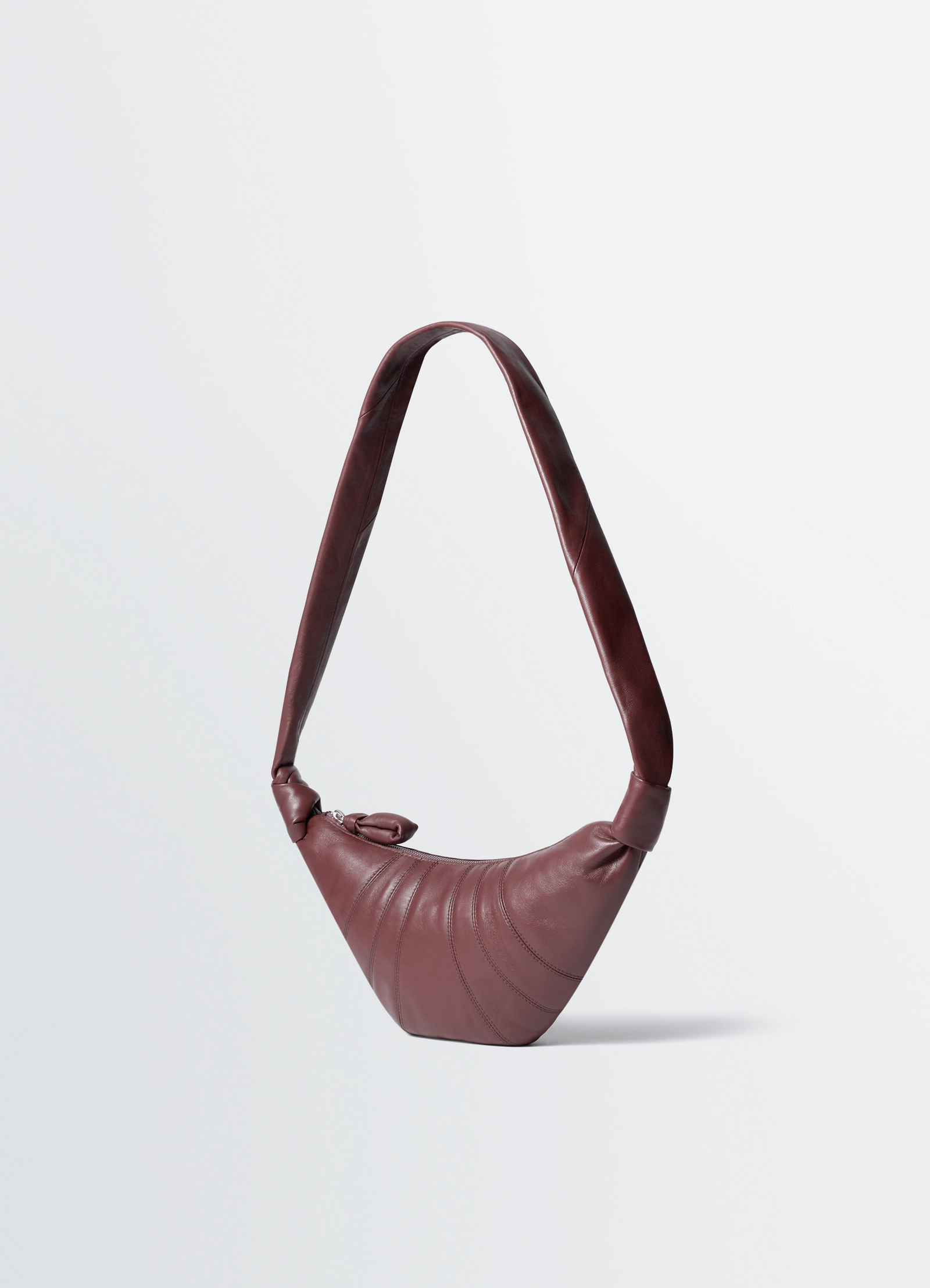 Small croissant bag in leather nappa lambskin, product shot, angled overhead view knotted handle detail