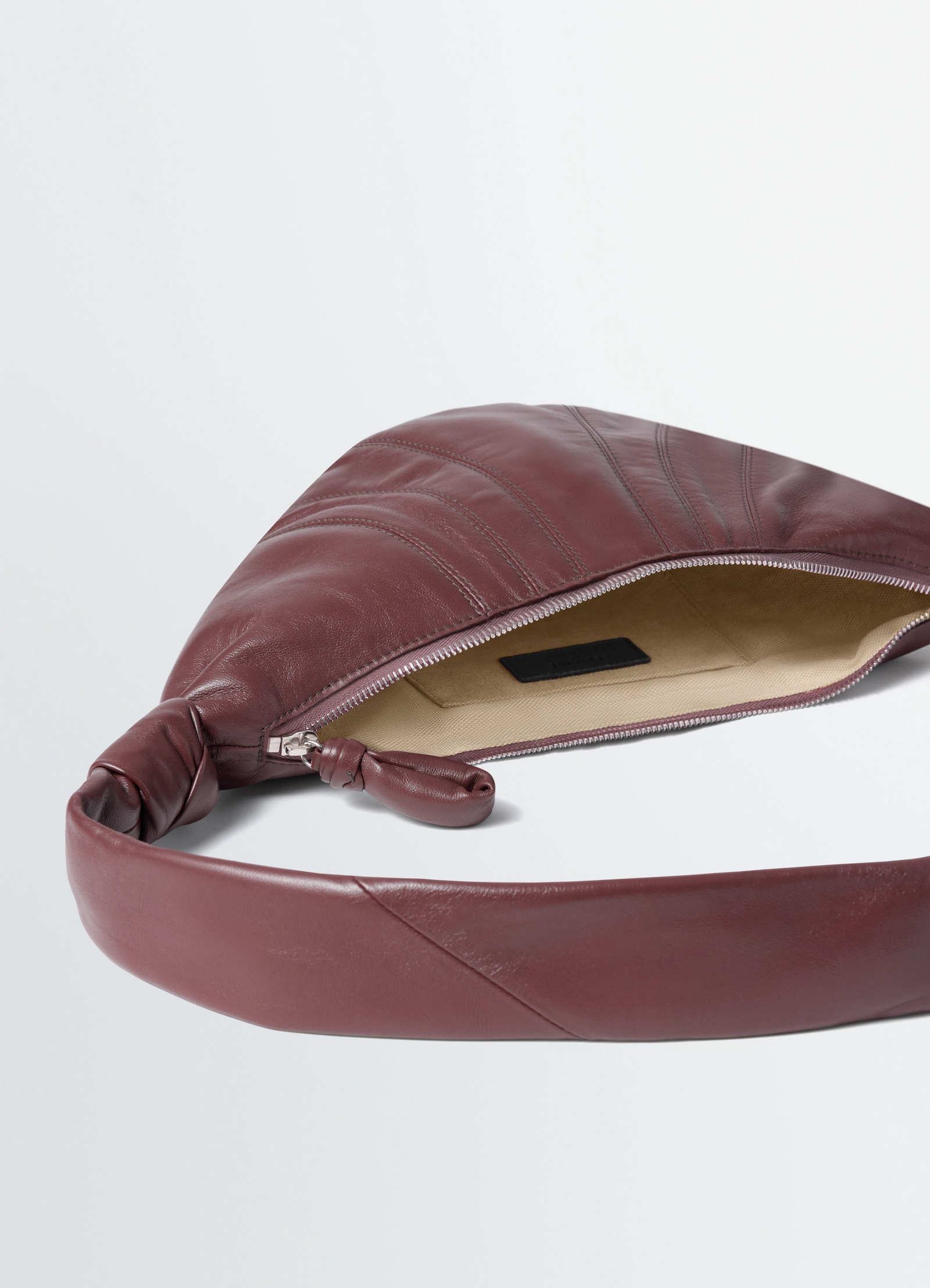 Small croissant bag in leather nappa lambskin, product shot, top detail view exposed zipper interior