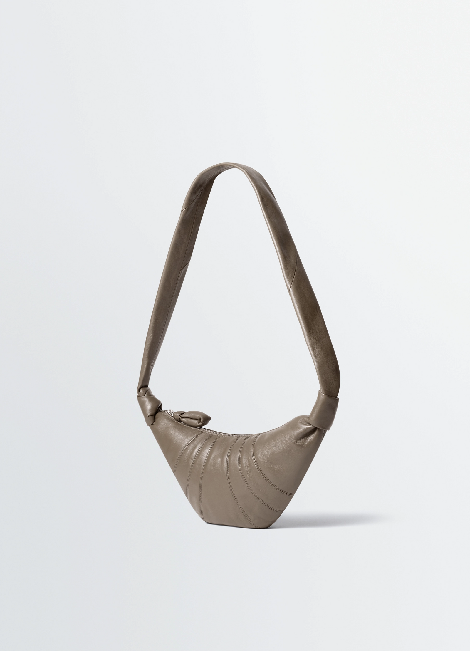 Small croissant bag in nappa lamb leather, product shot, three-quarter view twisted handle detail