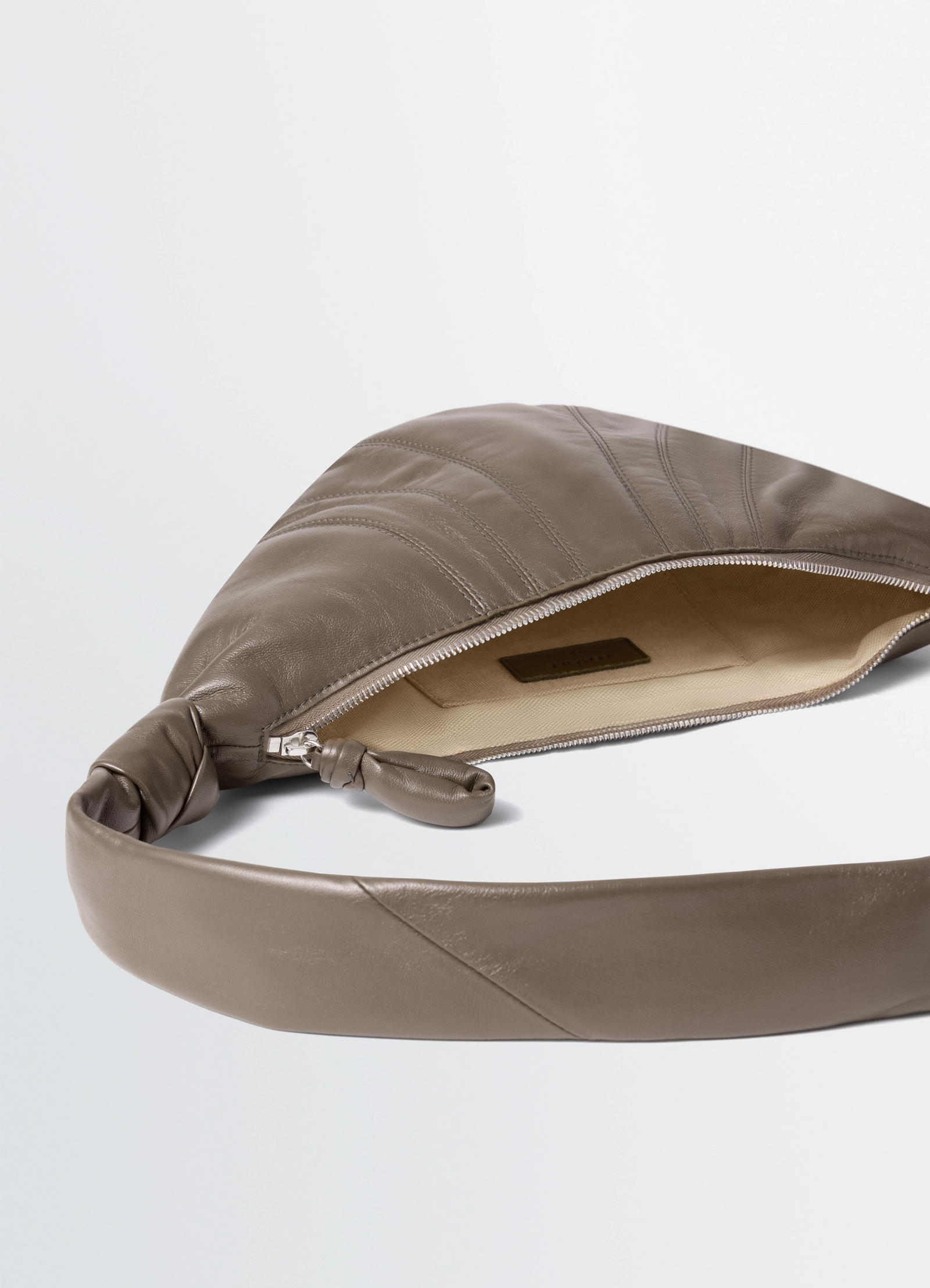 Small croissant bag in nappa lamb leather, product shot, zipper top detail open interior view