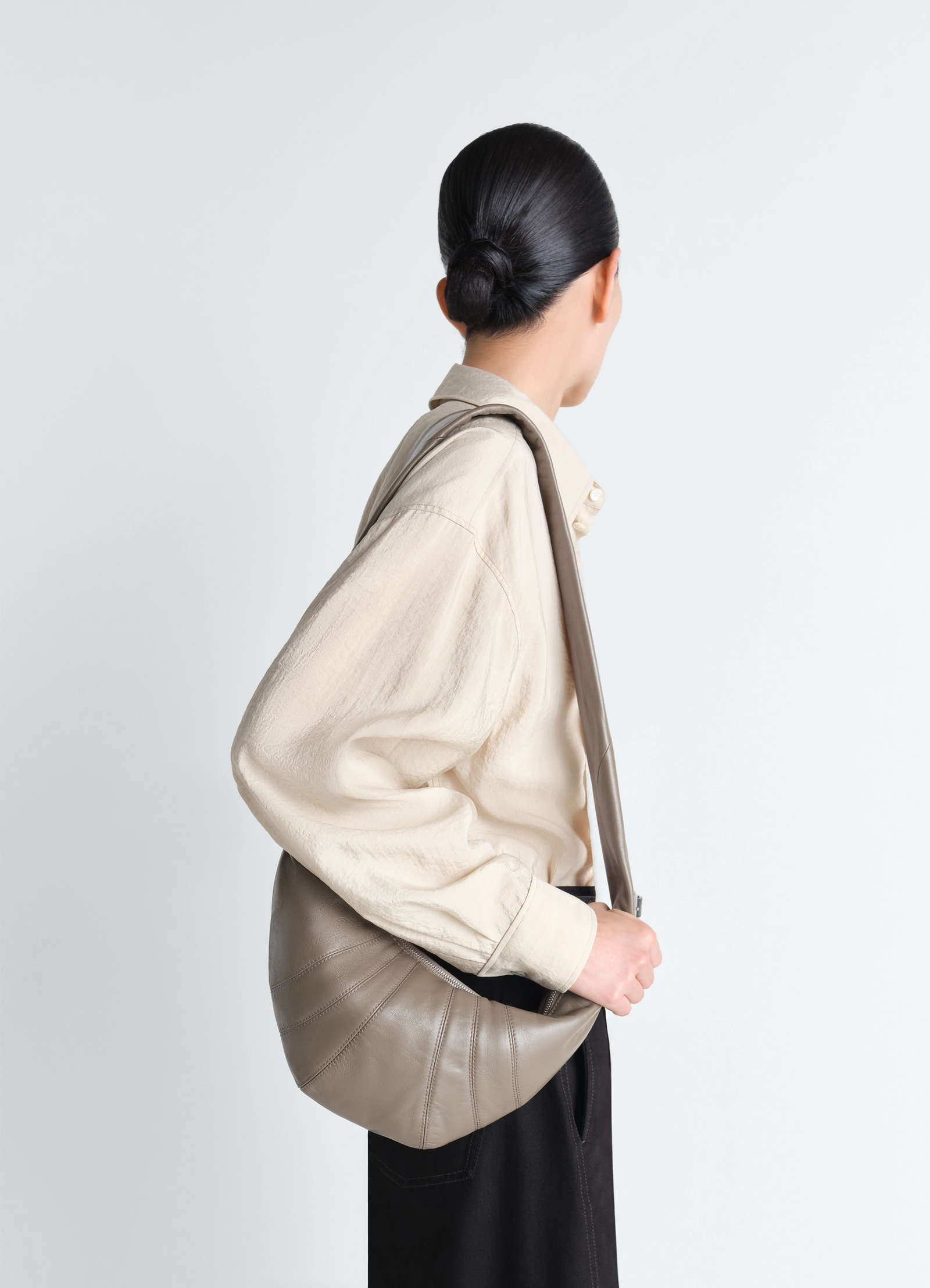 Small croissant bag in nappa lamb leather, model shot, side view curved shoulder strap