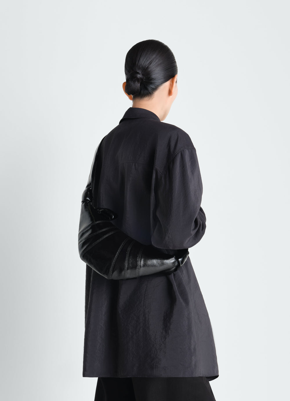 Small Croissant Bag in black coated cotton worn by model back view LEMAIRE