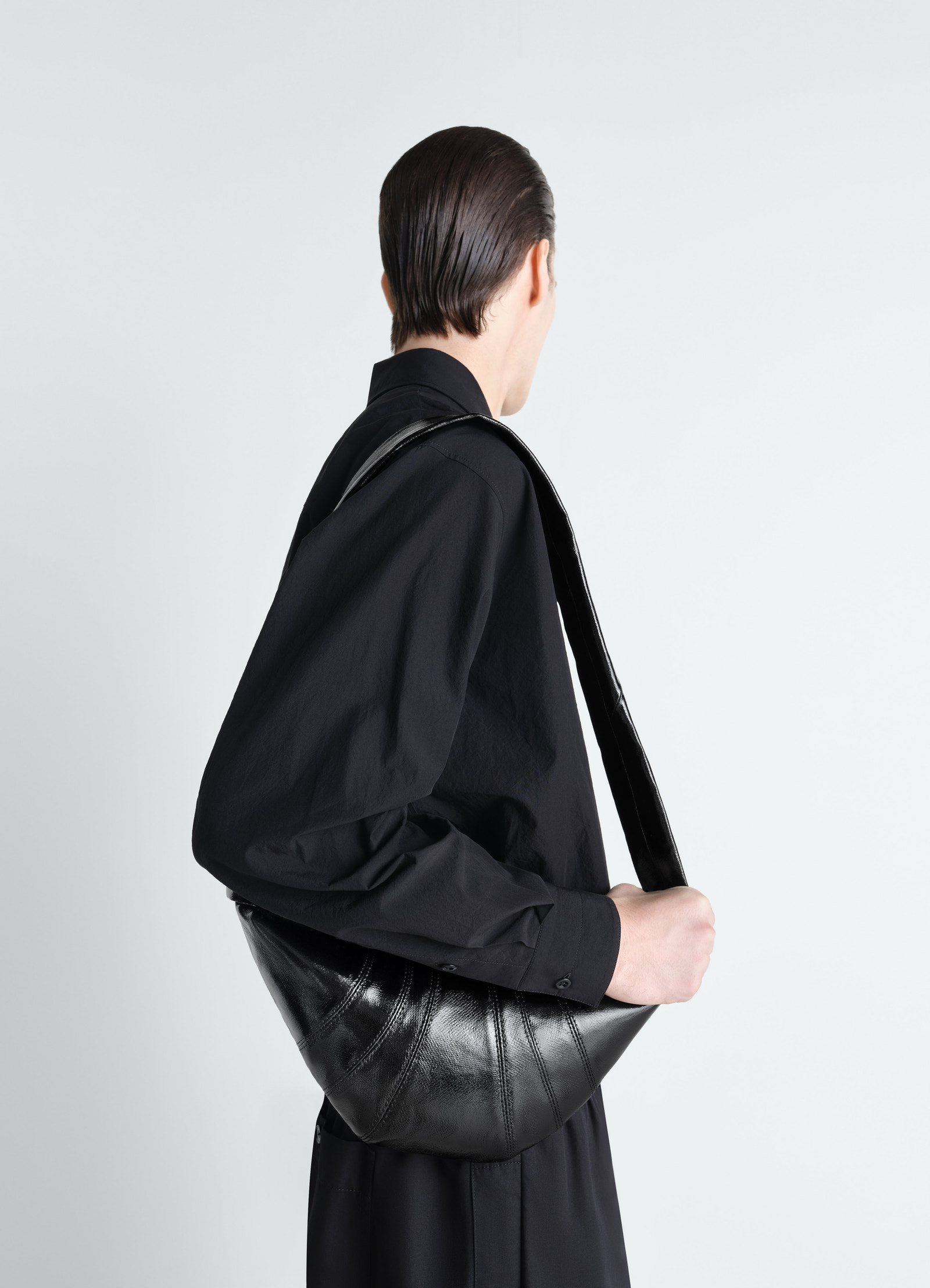 Small black coated cotton croissant bag lemaire worn by model side view with black shirt