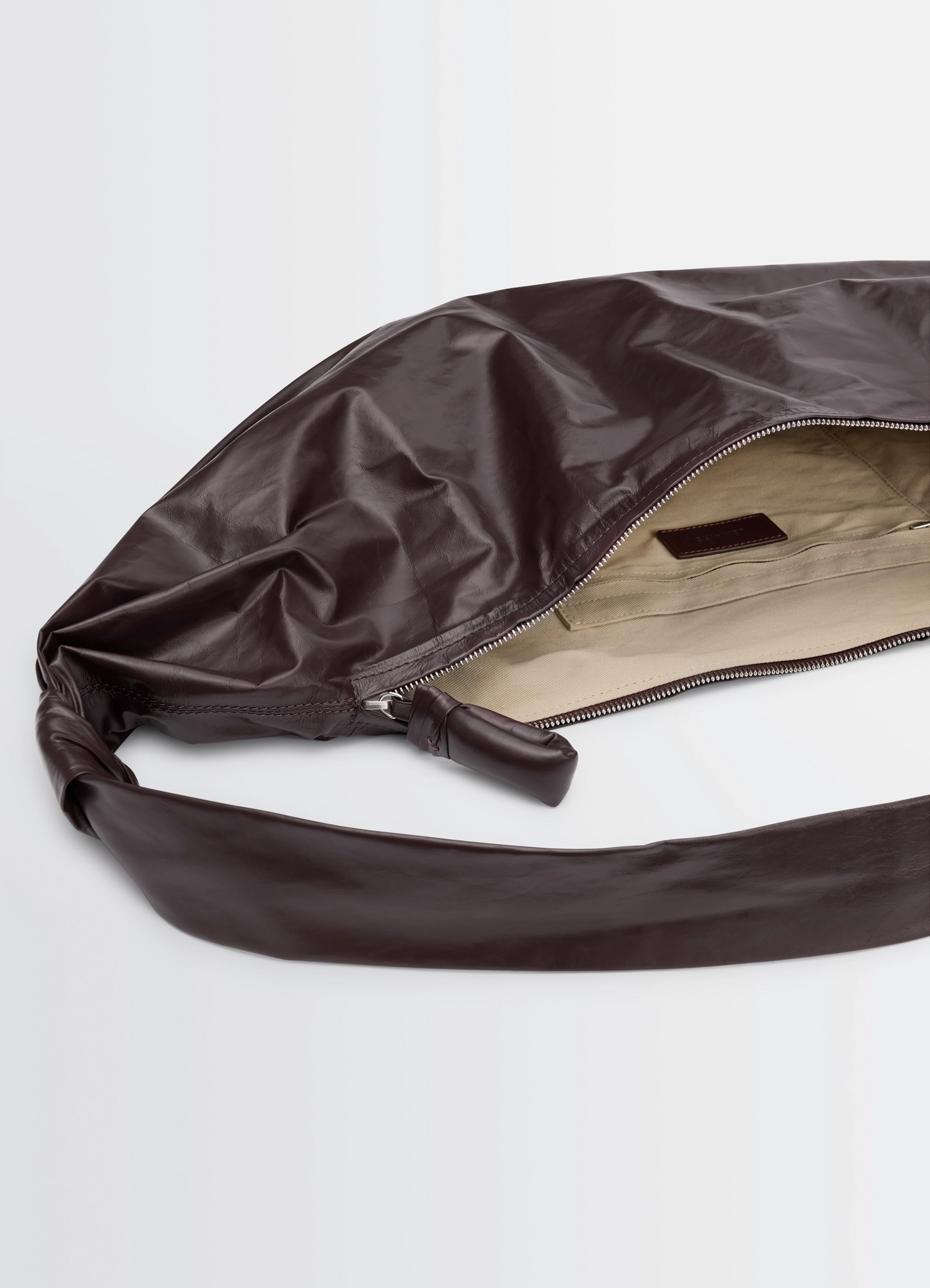 Large soft croissant bag in paper-effect leather, product shot, top-open view interior zipper detail