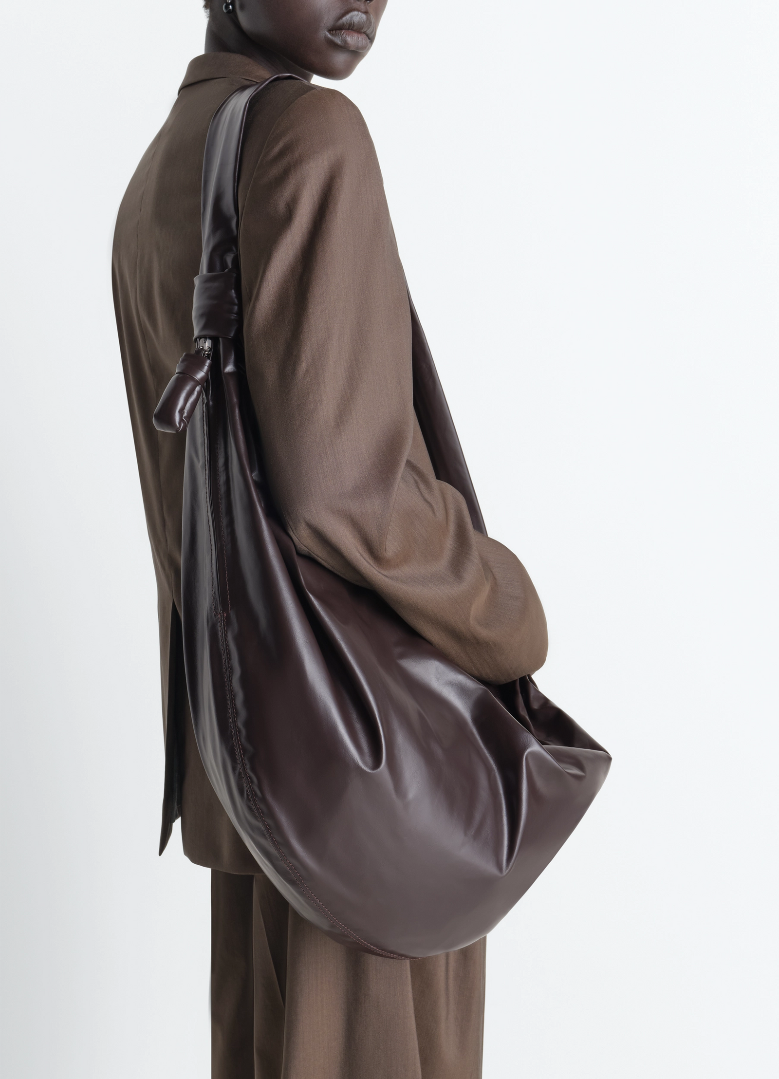 Large soft croissant bag in paper-effect leather, model shot, over-shoulder view soft texture drape