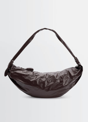Large soft croissant bag lemaire in dark brown paper leather front view on plain white background