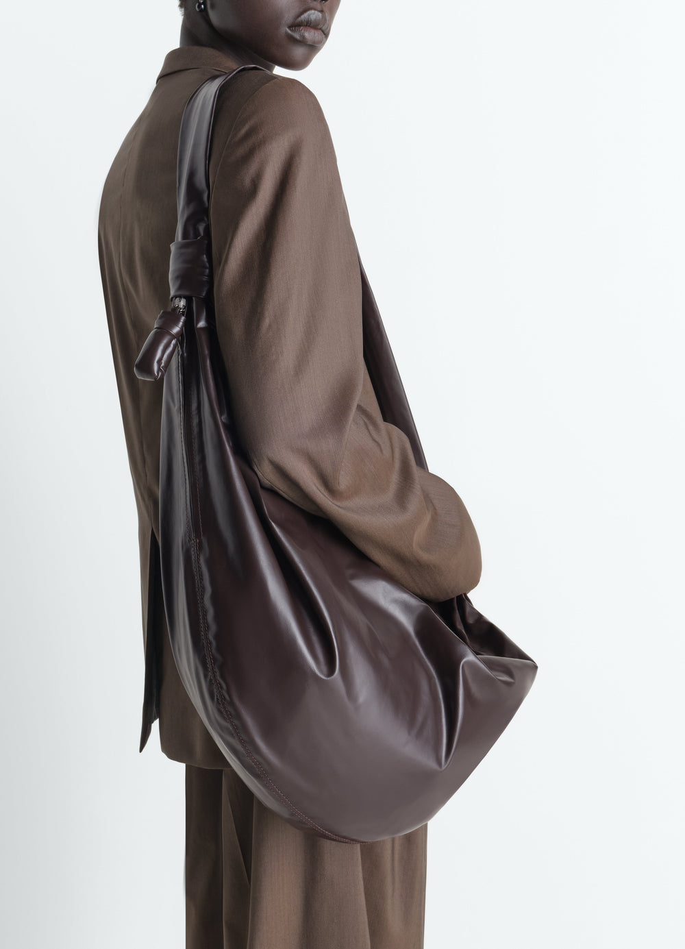 Large soft croissant bag in dark brown paper leather LEMAIRE worn by model side view