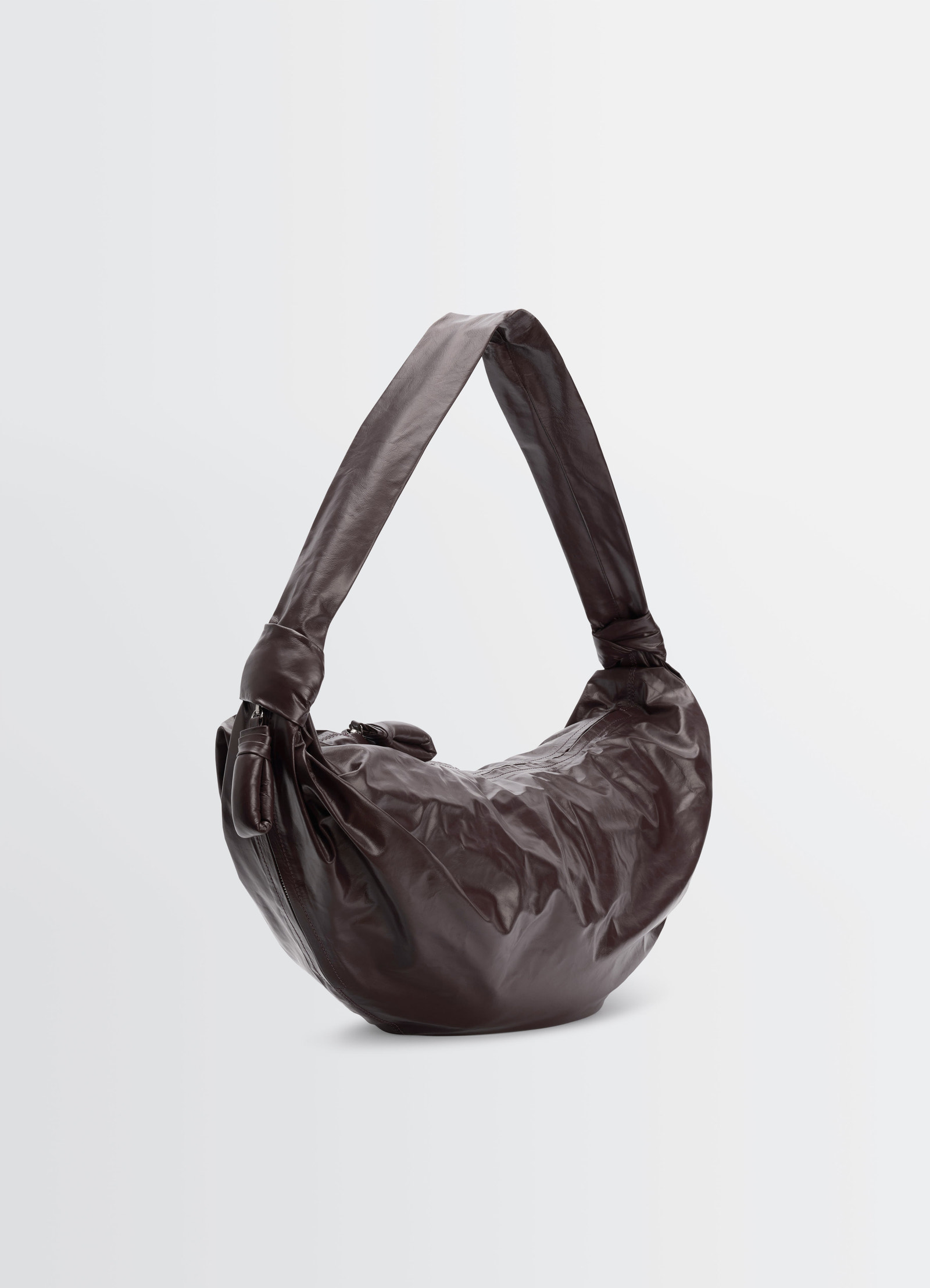 Large soft croissant bag in dark brown paper leather by lemaire, front view on plain white background