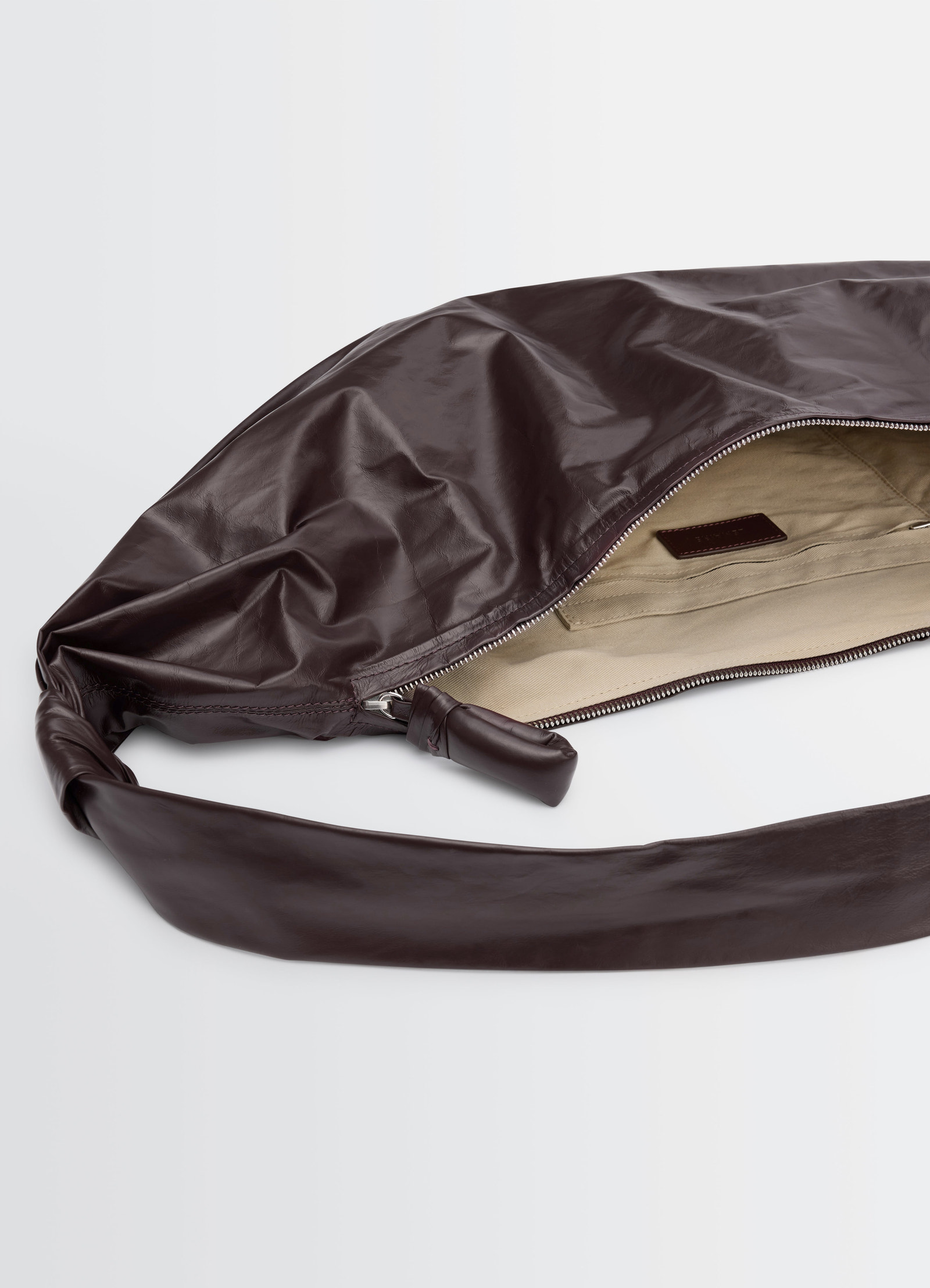 Large soft croissant bag in dark brown paper leather by lemaire close-up of open zipper and beige lining