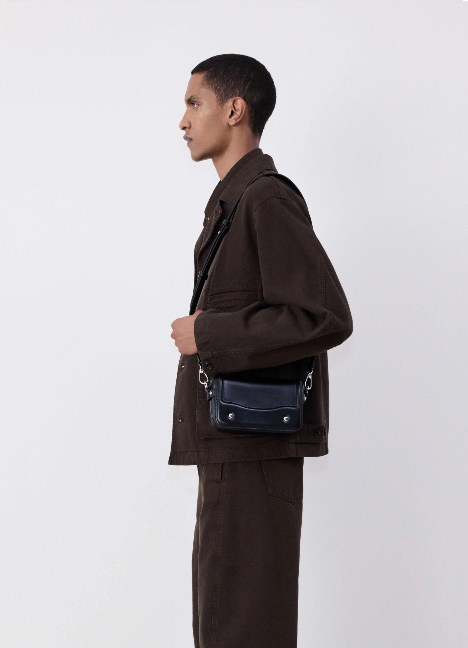 Lemaire ransel mini satchel in glossy black vegetable-tanned leath, model shot, side view double button closure