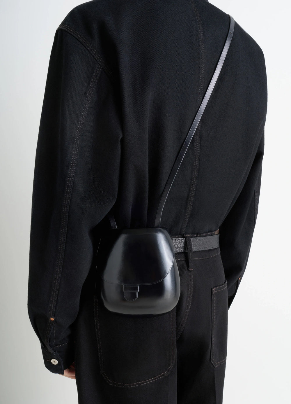 Il Bussetto for Lemaire Small Cartr in Patinated Vegetable-Tanned Leather, model shot, over shoulder view fitted black garmen