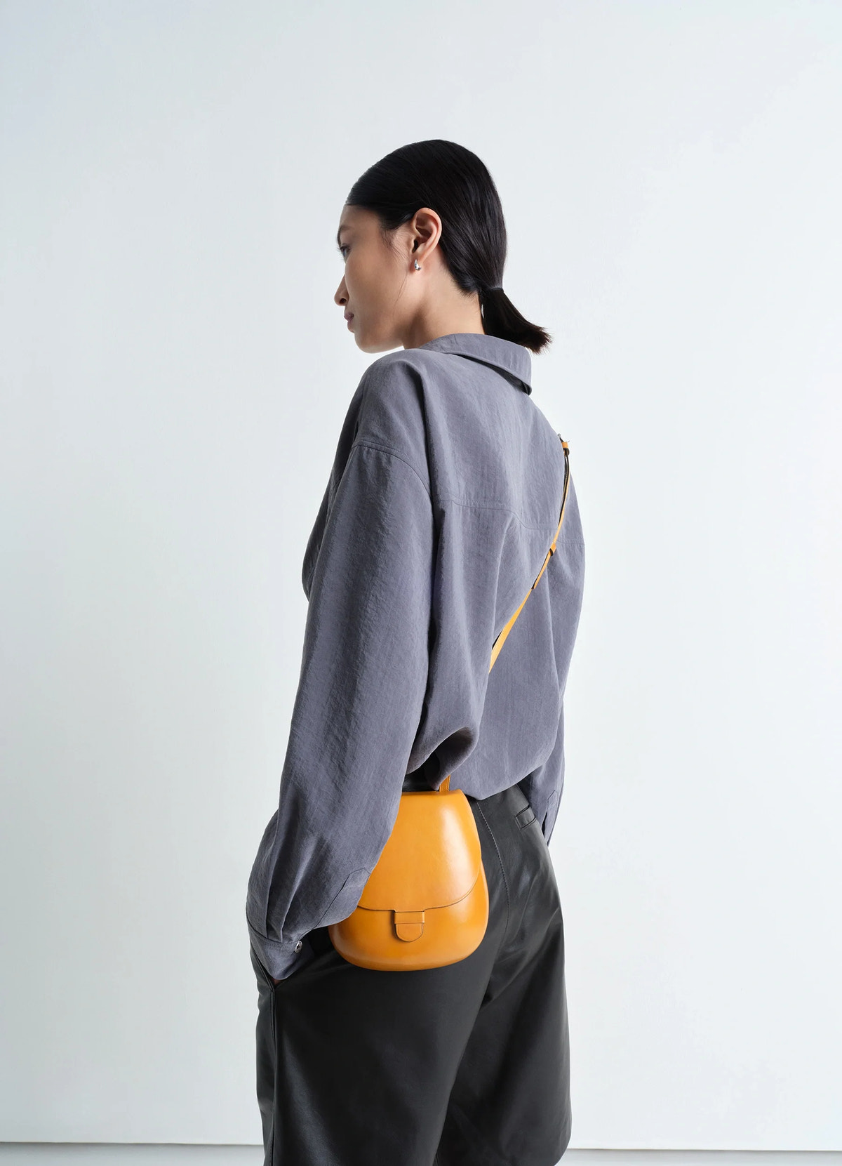 Il bussetto for lemaire small cartr in vegetable-tanned cowhide, model shot, back side view adjustable strap worn cross-body