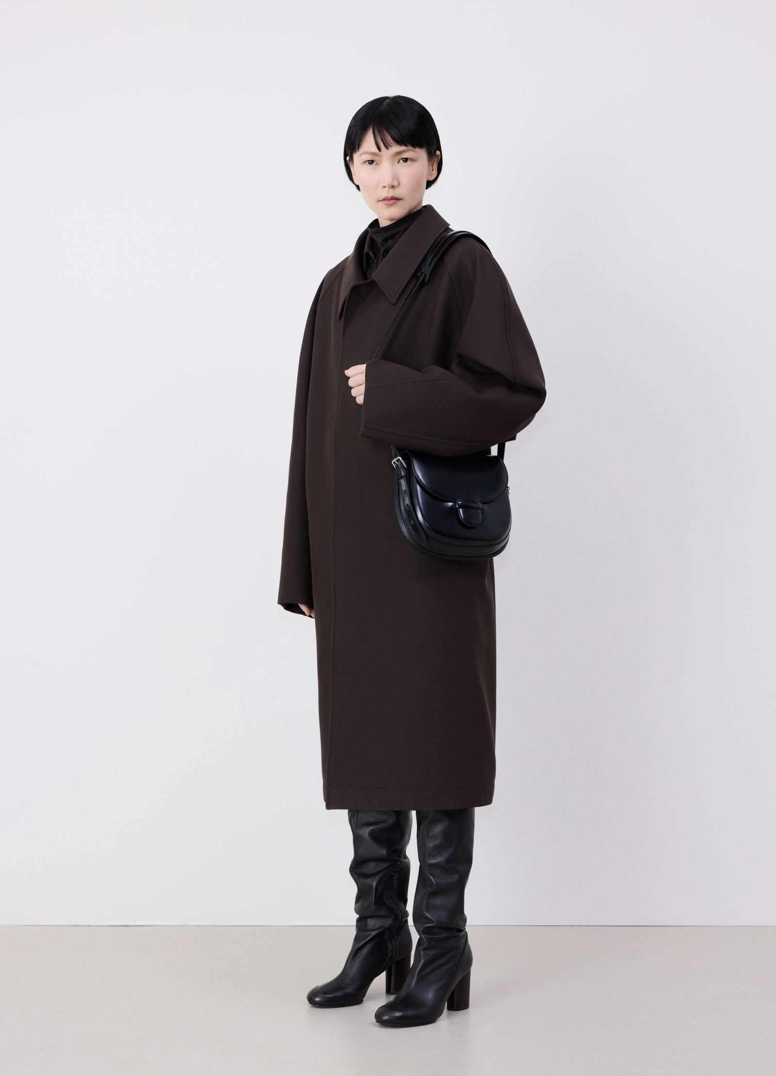 Lemaire cartridge sport bag in black vegetable-tanned leather, model shot, side view crossbody overcoat