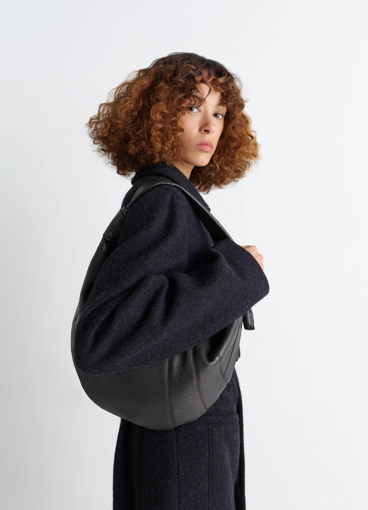 Fortune Croissant Bag in Grained Leather Black, model shot, Side view Knotted elements visible