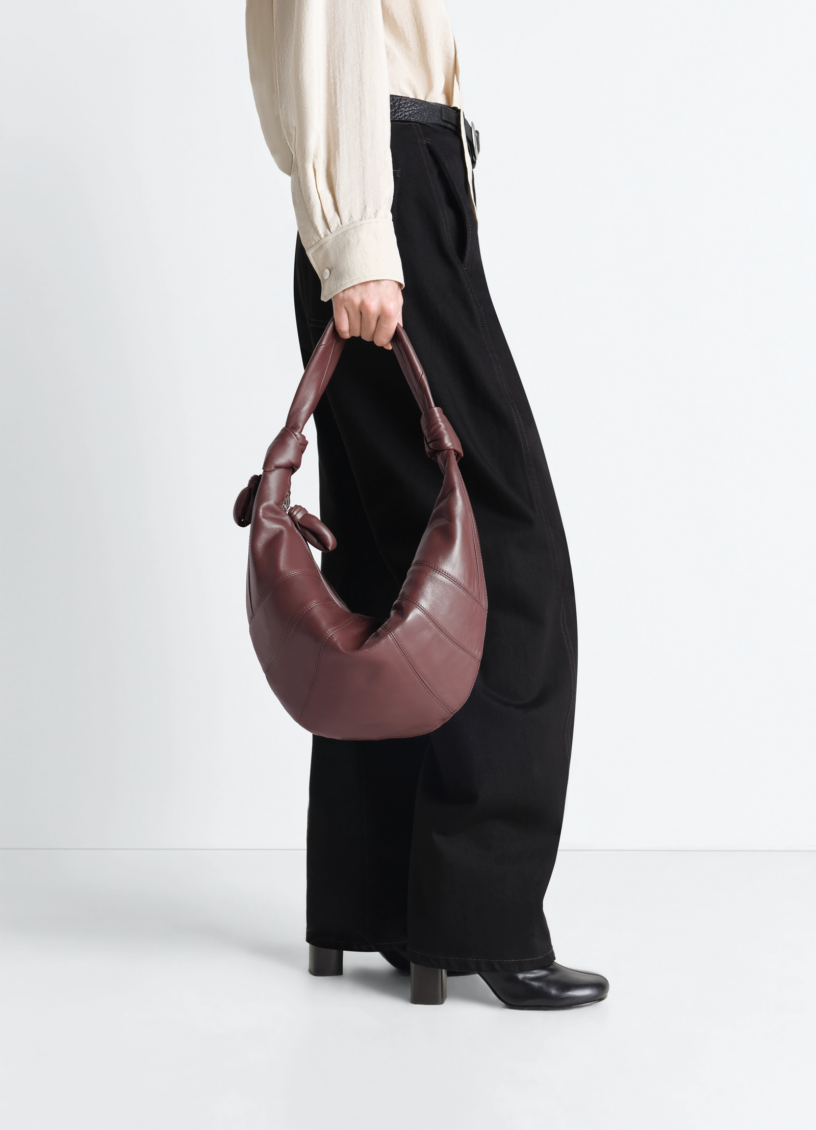 Fortune croissant bag in leather, model shot, held by model curved strap design