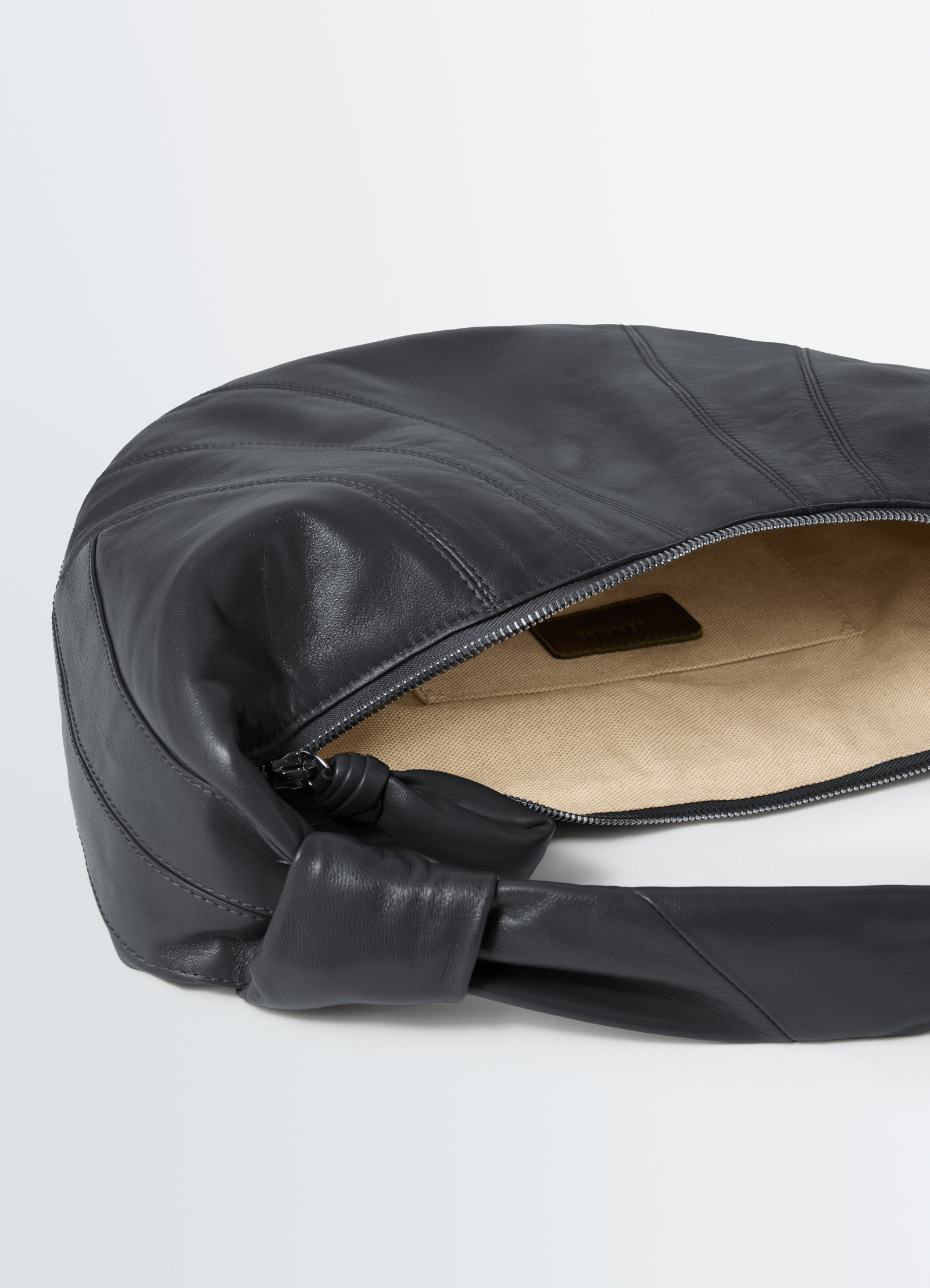Fortune croissant bag lemaire black leather with beige interior shown open on plain background close-up detail