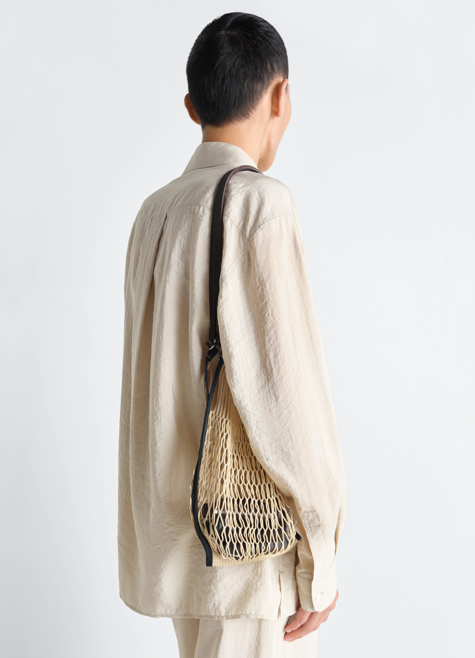 Medium filt net shopping bag in nylon mesh and leather, model shot, back view sling shoulder wear