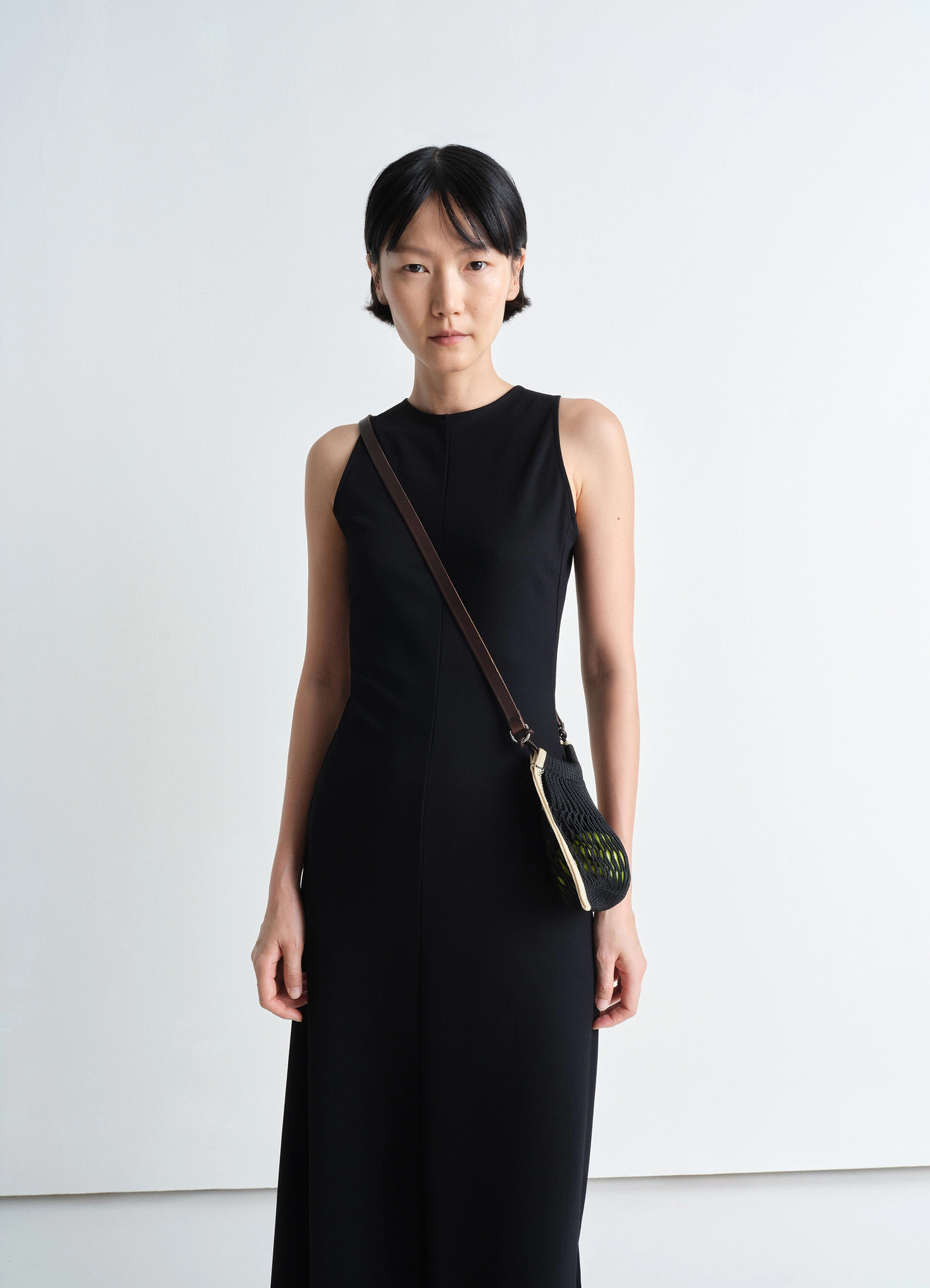 Mini crossbody filt net bag in dark chocolate leather, nylon, model shot, front view crossbody worn over black dress