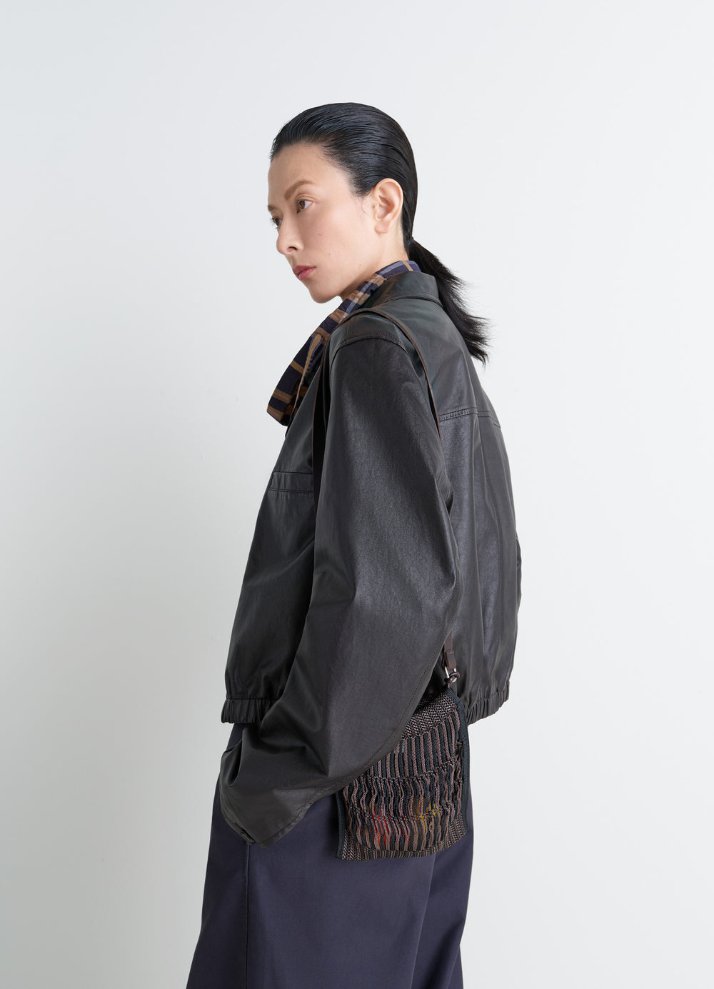 Lemaire MINI CROSSBODY FILT NET BAG in Nylon mesh, vegetable-tanned leathe, model shot, back view layered over jacket
