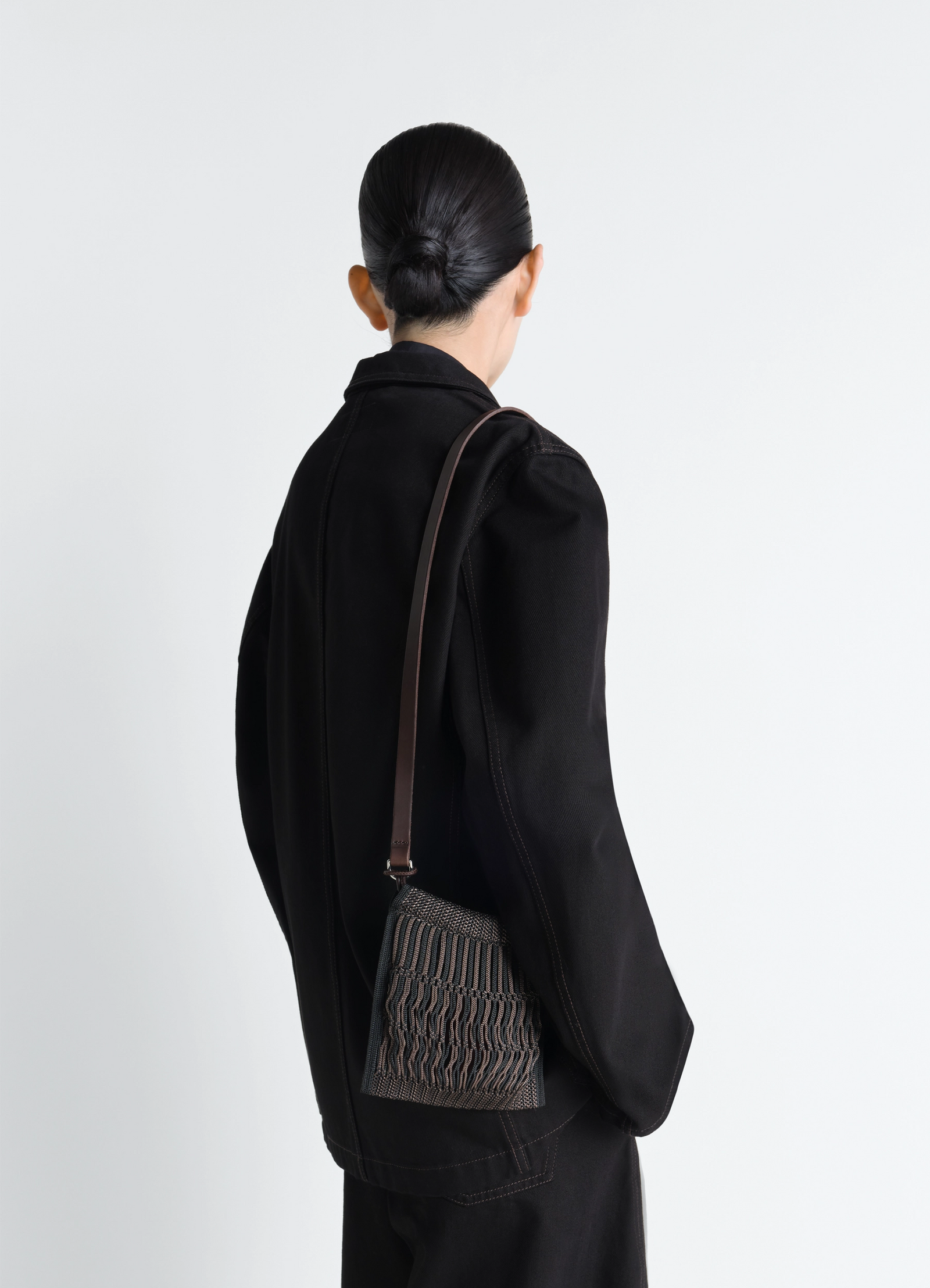 Lemaire mini crossbody filt net bag in nylon mesh with leather strap, model shot, back view textured leather strap